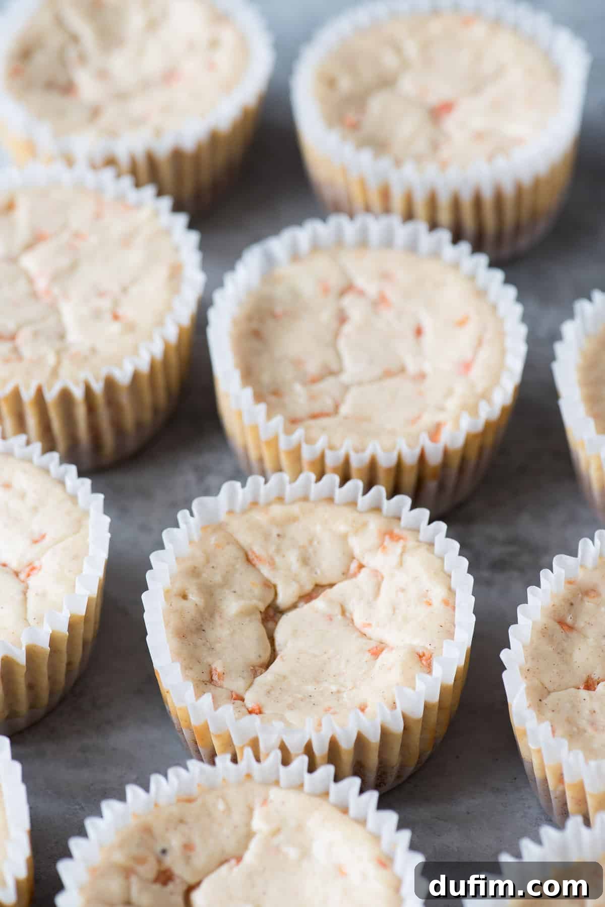 Spiced Carrot Cheesecake Minis 3 Rows of plain mini carrot cheesecakes cooling in a muffin pan, showcasing their simple elegance.