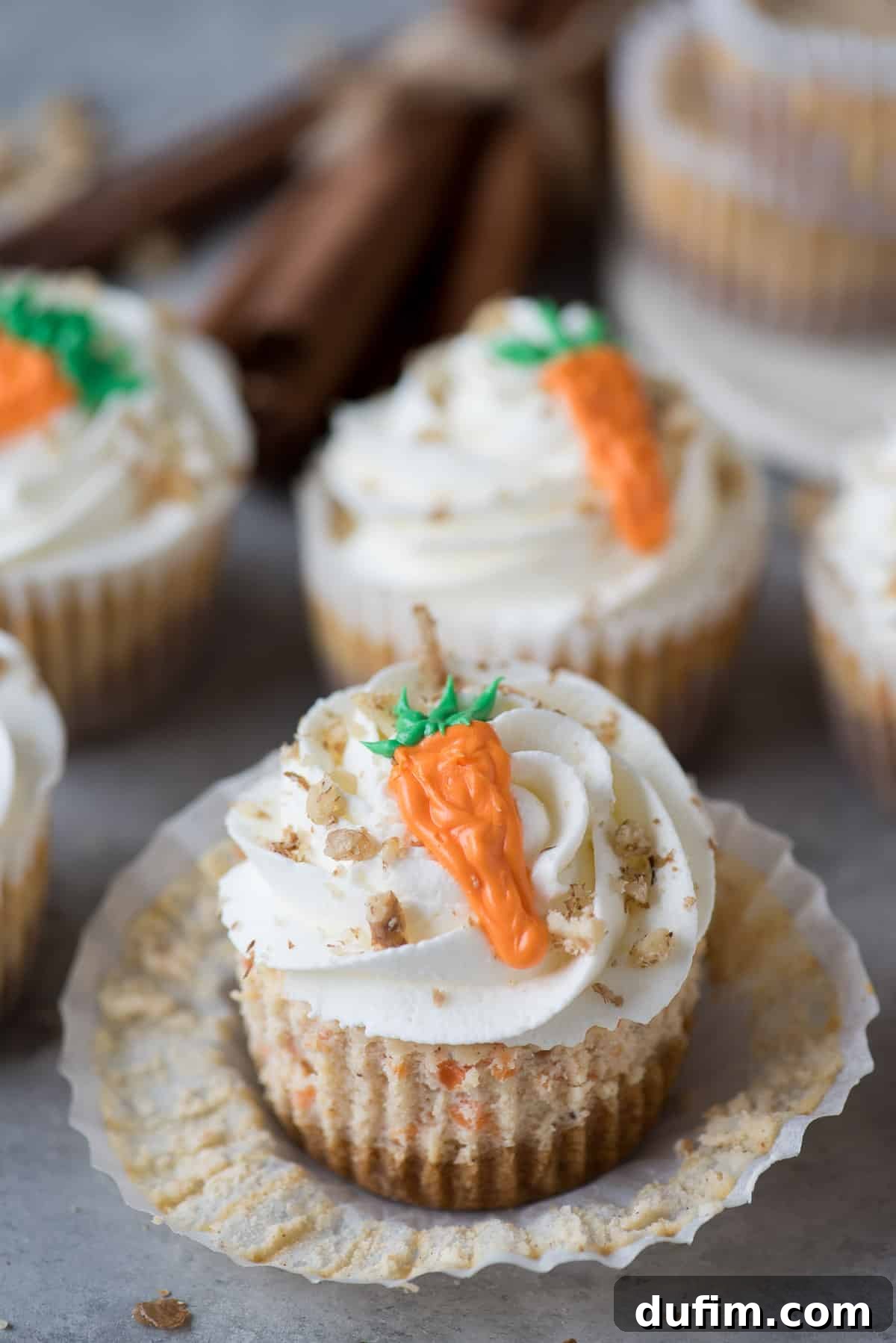 Spiced Carrot Cheesecake Minis 4 Mini carrot cheesecake topped with whipped cream and a small piped frosting carrot.