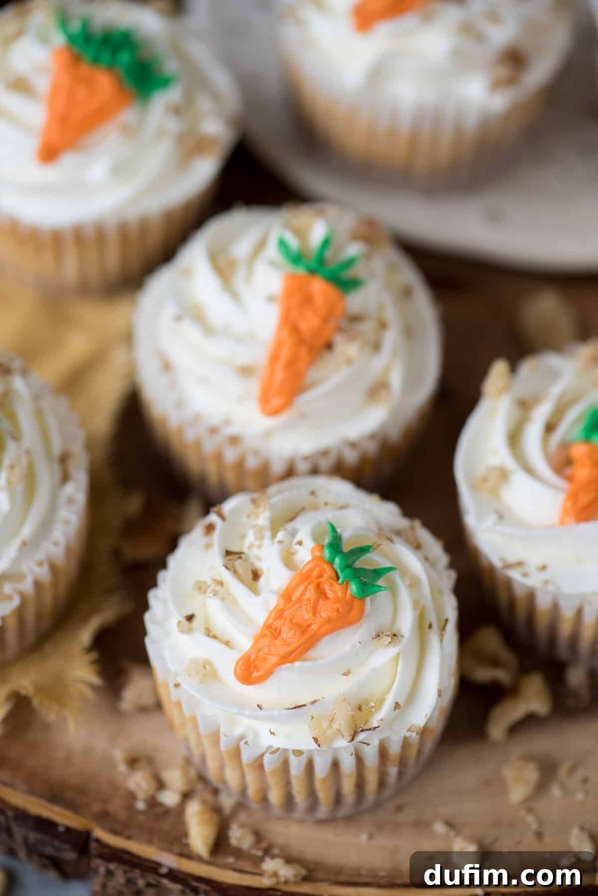 Spiced Carrot Cheesecake Minis 5 Mini carrot cheesecakes with piped frosting carrots on a rustic wooden background.