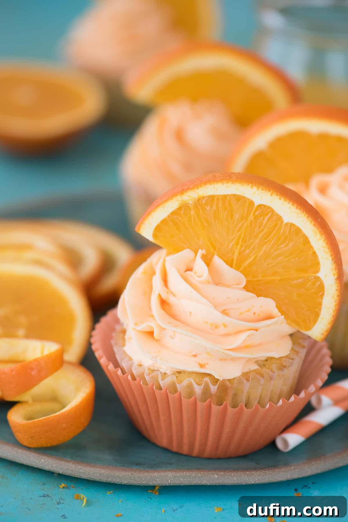 Orange Poppy Seed Cupcakes: A Zesty Citrus Delight A beautifully frosted Orange Poppy Seed Cupcake, garnished with a fresh orange slice, set against a calming blue background.