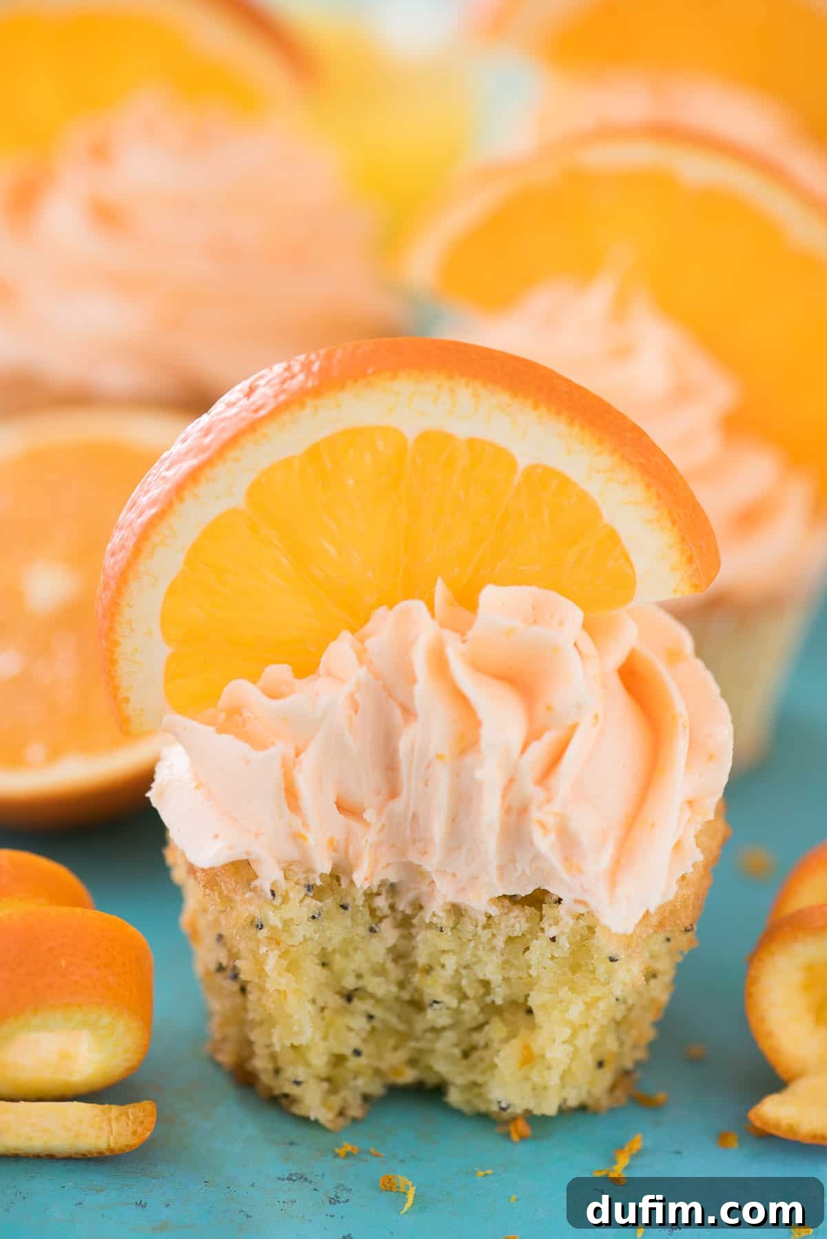 Fresh Orange Zest and Juice for Authentic Flavor Close-up of an Orange Poppy Seed Cupcake with vibrant orange frosting and a fresh orange slice on top, highlighting its irresistible appeal.