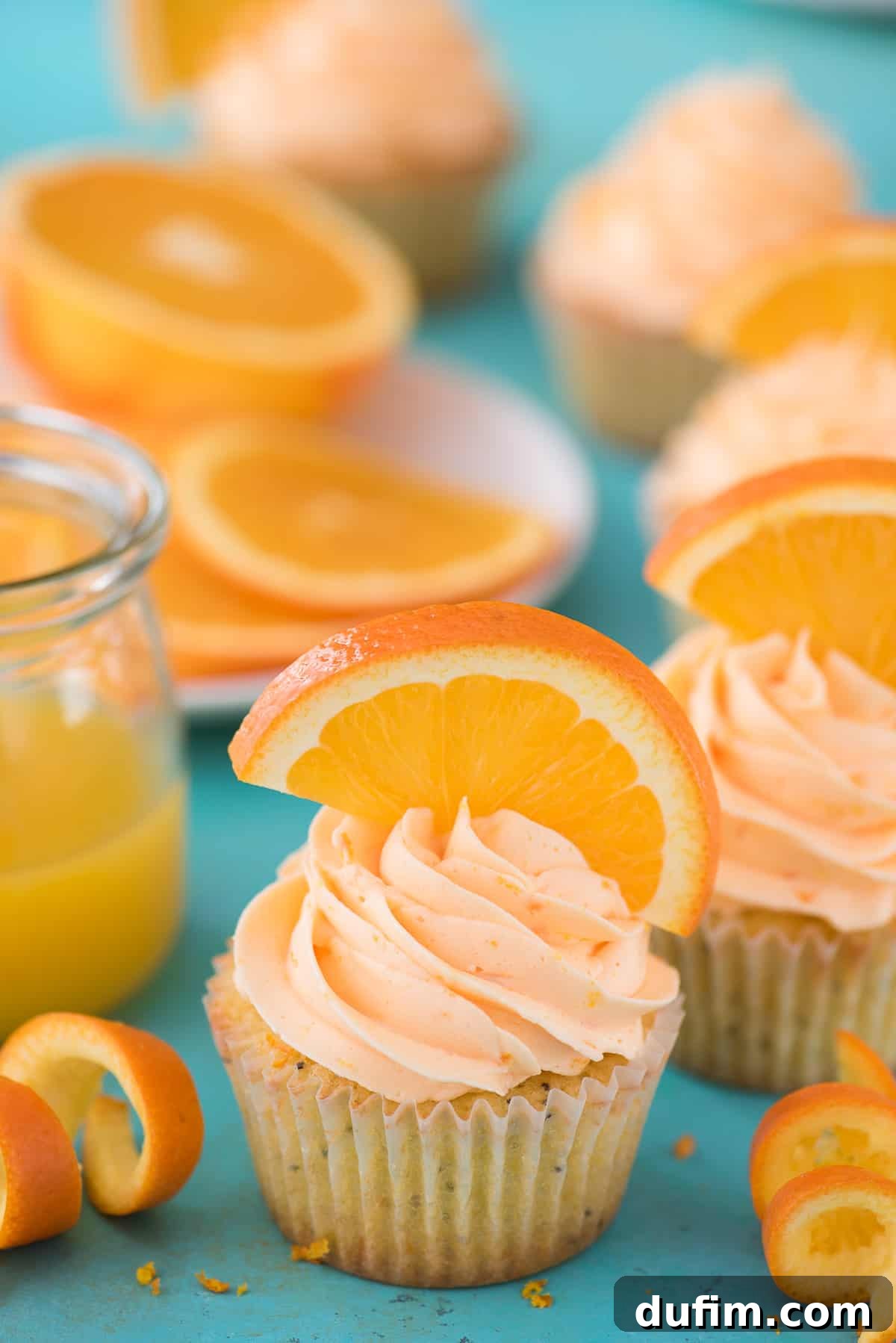 Perfectly Zesty and Moist Orange Poppy Seed Cupcakes A trio of Orange Poppy Seed Cupcakes, showcasing the delicate orange frosting and poppy seeds within the cake, ready to be enjoyed.