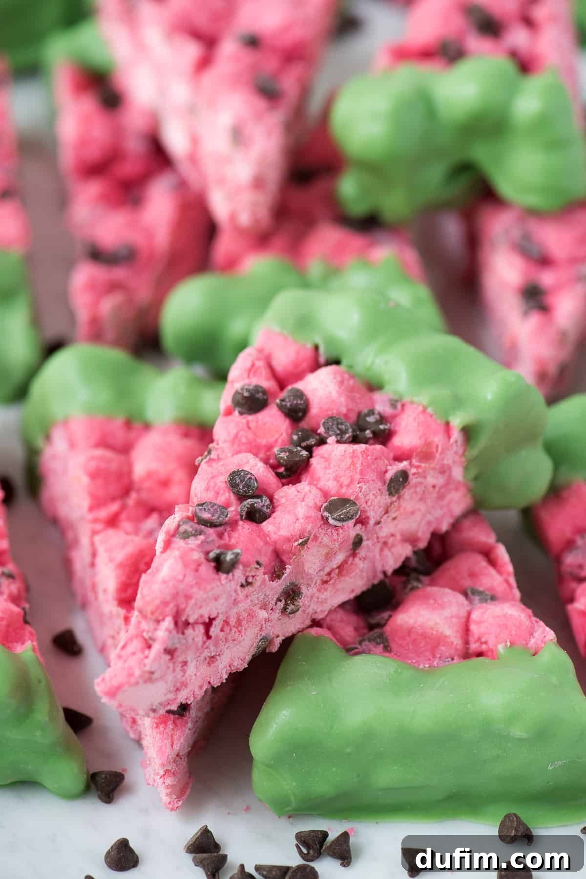 Three perfectly shaped watermelon marshmallow slices on a white plate.
