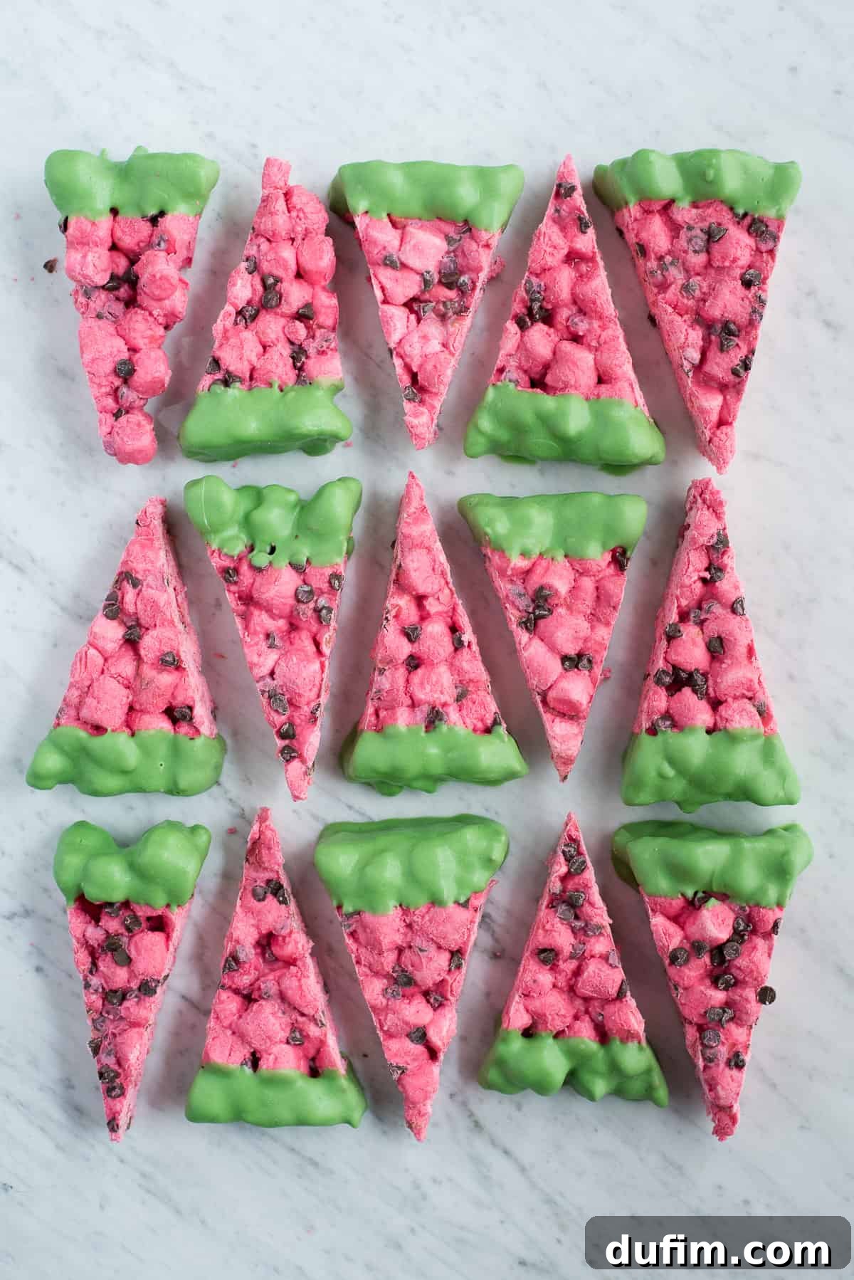 A tray filled with pink marshmallow mixture and mini chocolate chips, pressed into a pan.