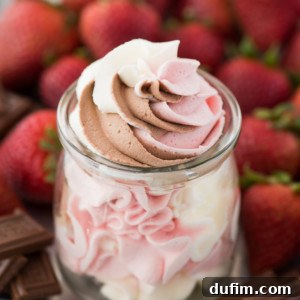 A small glass jar filled with swirled Neapolitan whipped cream—chocolate, strawberry, and vanilla—surrounded by fresh strawberries and pieces of chocolate.