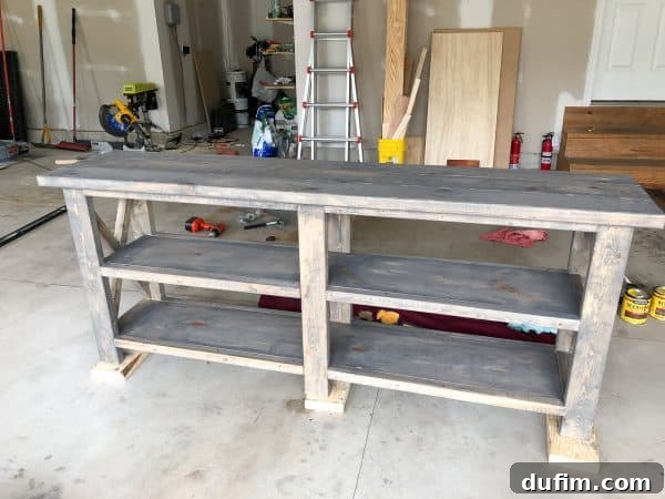 Applying a second coat of dark walnut stain over the gray base on the console table
