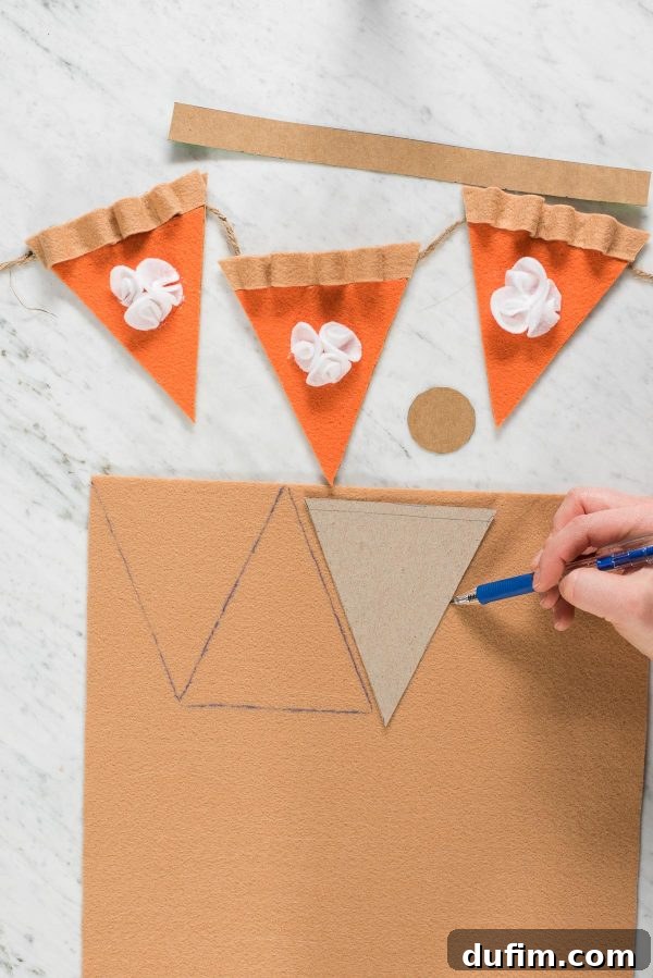 Felt Pie Crust Template Tracing for DIY Garland Tracing the pie crust template onto a large tan felt sheet using a pen, with scissors nearby for cutting.