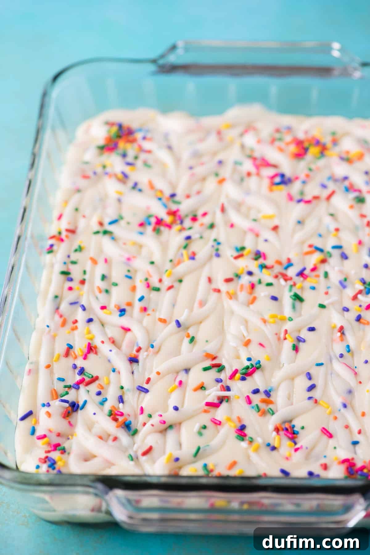 The finished Funfetti Earthquake Cake batter in the glass 9x13 inch pan, now topped with extra rainbow sprinkles, ready for baking.