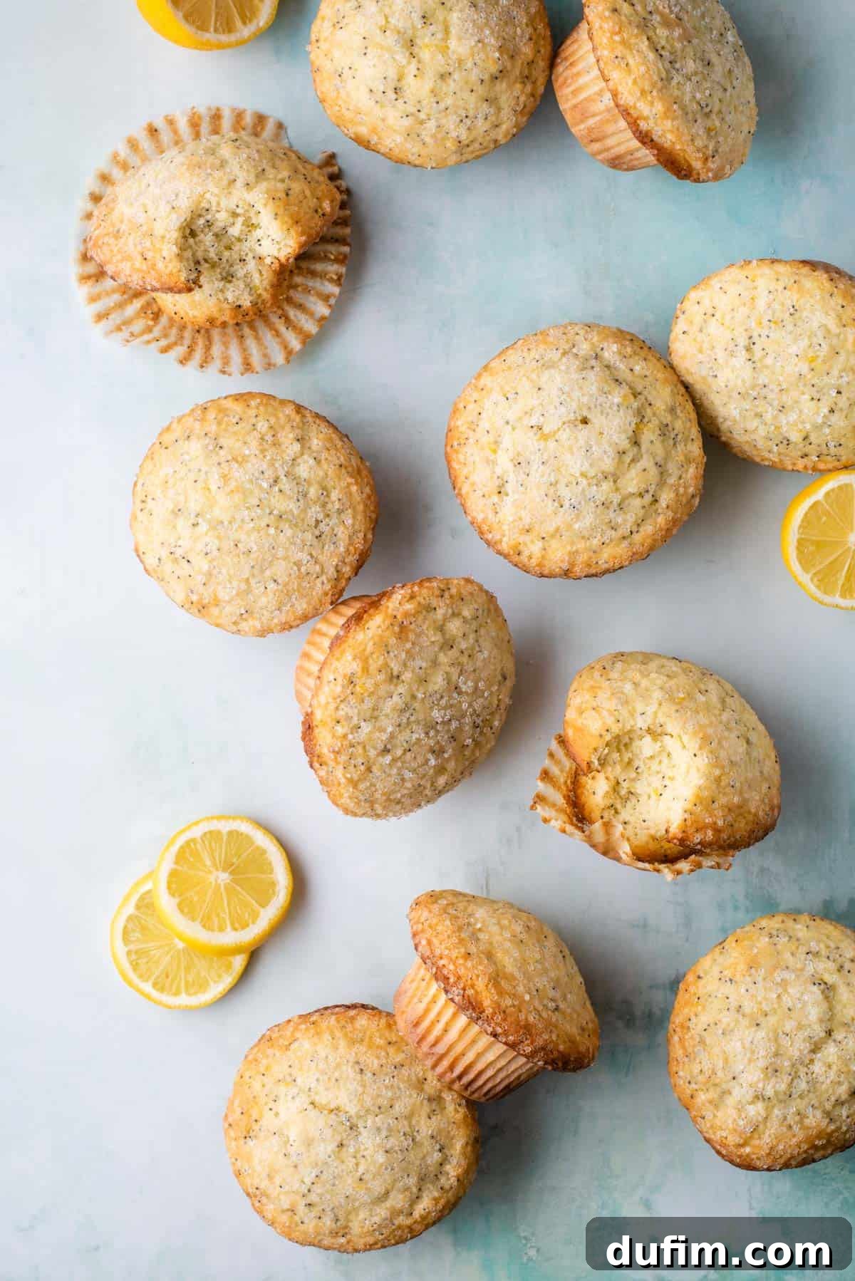 Zesty Lemon Poppy Seed Delights 5 An inviting display of baked lemon poppy seed muffins, some arranged upright and others on their sides, surrounded by bright yellow lemon slices, emphasizing their fresh and zesty appeal.