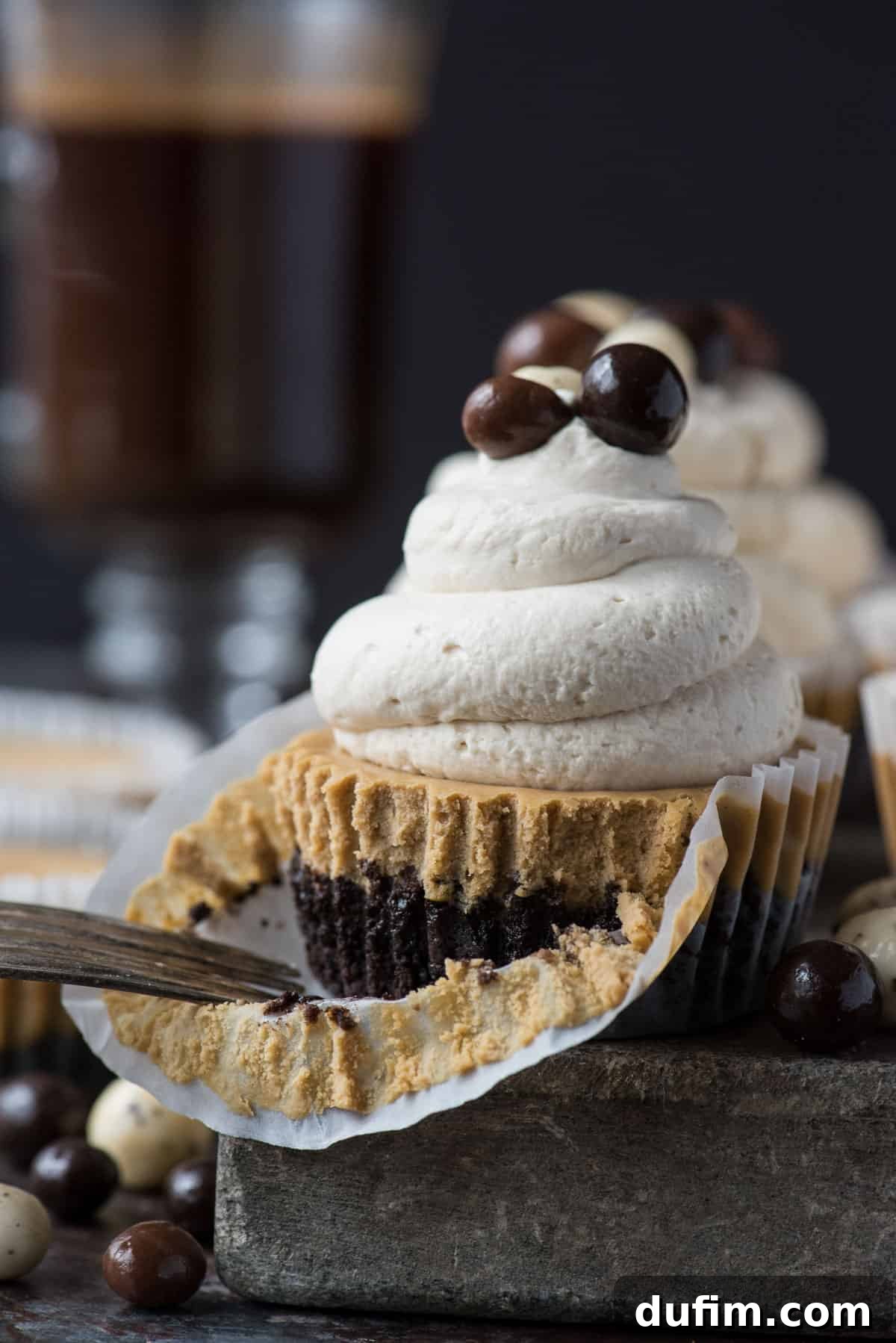 This is a crowd favorite mini coffee cheesecake recipe that you’ll use over and over! The whole recipe is only 7 ingredients and you make it in a regular size muffin pan! Plus, you can do an oreo crust or graham cracker crust for these mini espresso cheesecakes. #minicheesecake #coffeecheesecake #minicoffeecheesecake #espressocheesecake #mochacheesecake A stunning mini coffee cheesecake, adorned with a swirl of whipped cream and delicate espresso beans, resting on a sophisticated stone slab. Additional espresso beans are scattered around, creating an inviting and luxurious dessert scene.