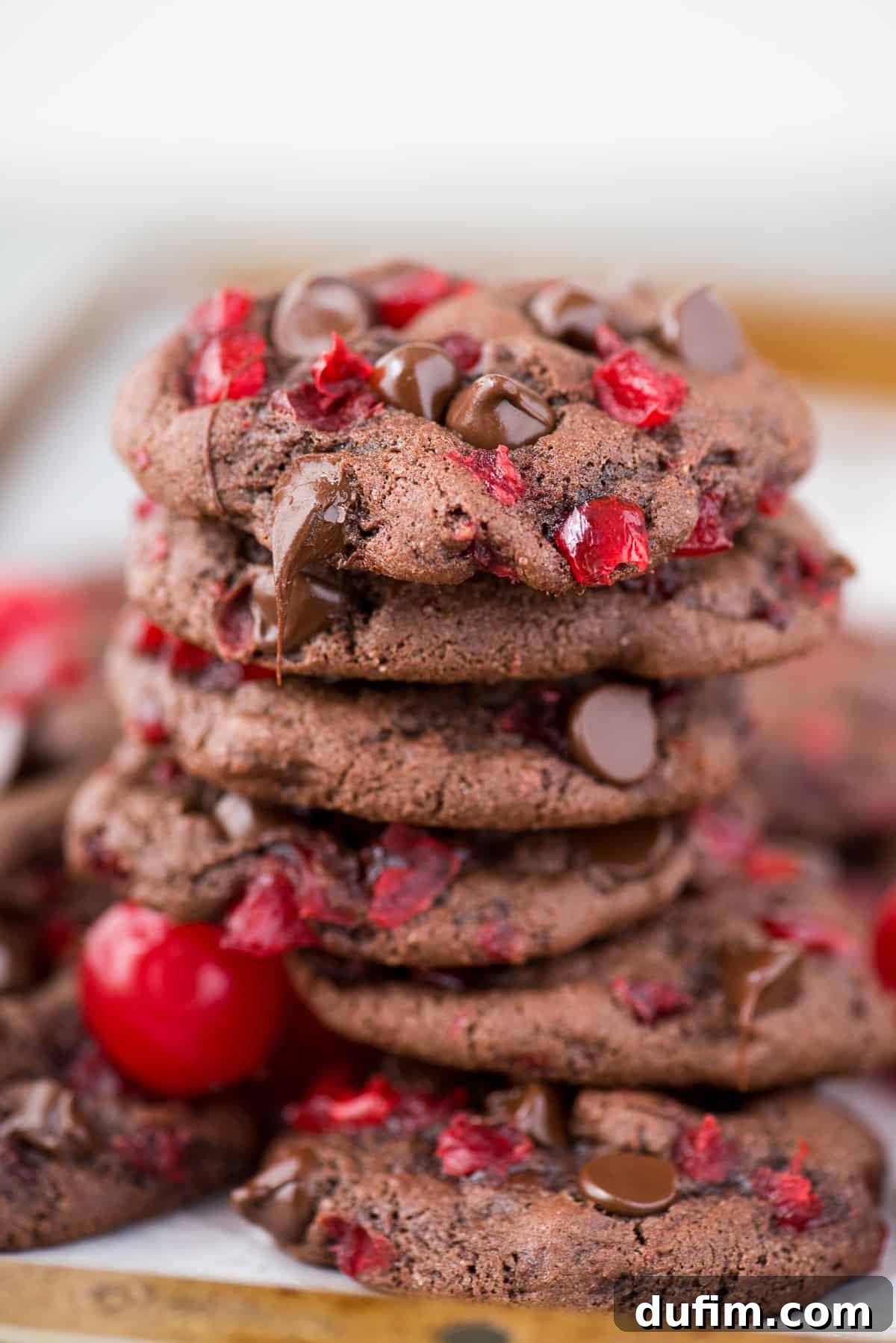 black forest cookies with maraschino cherries and chocolate chips stacked in a pile on metal baking sheet