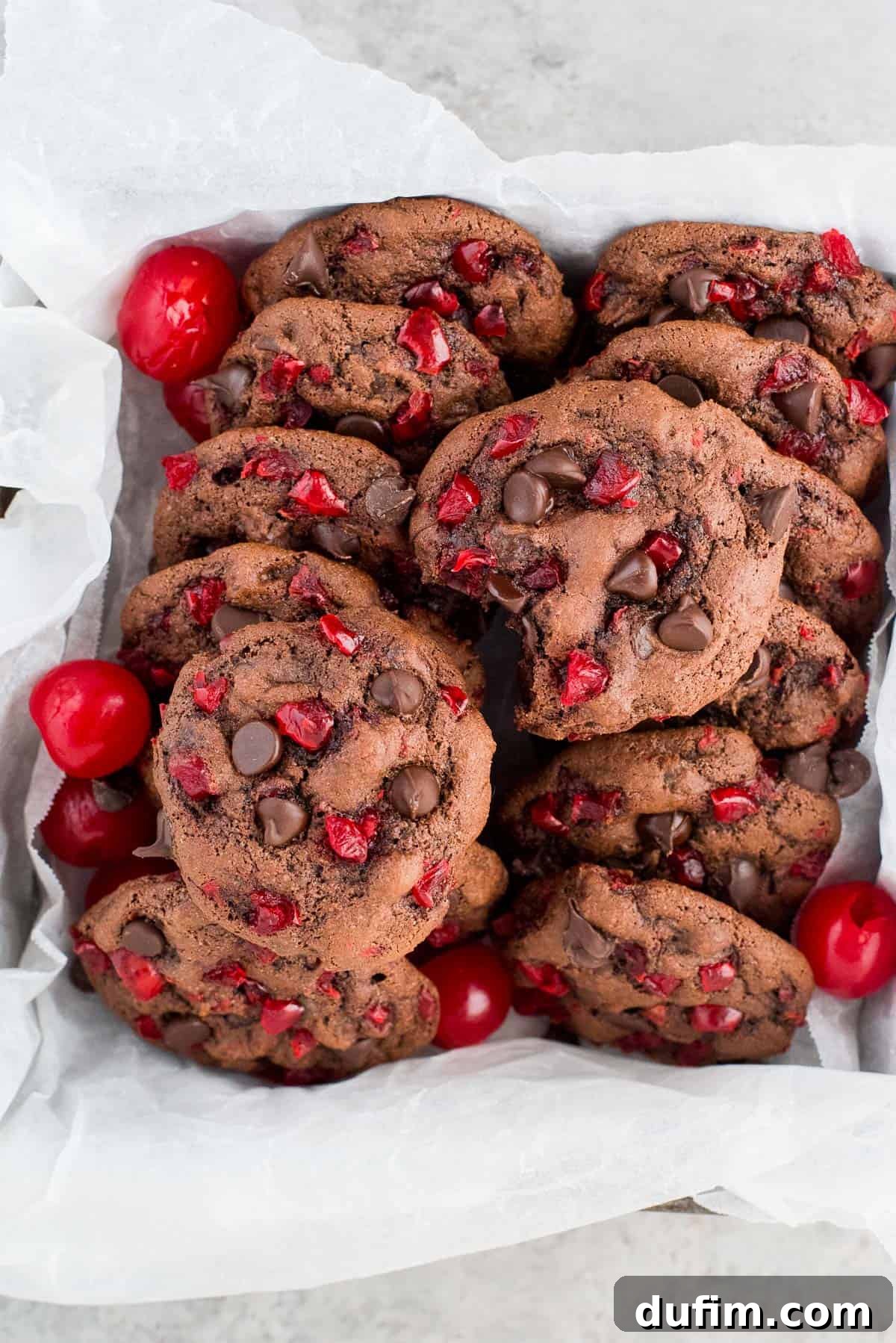 black forest cookies with maraschino cherries and chocolate chips lined in a container with white paper