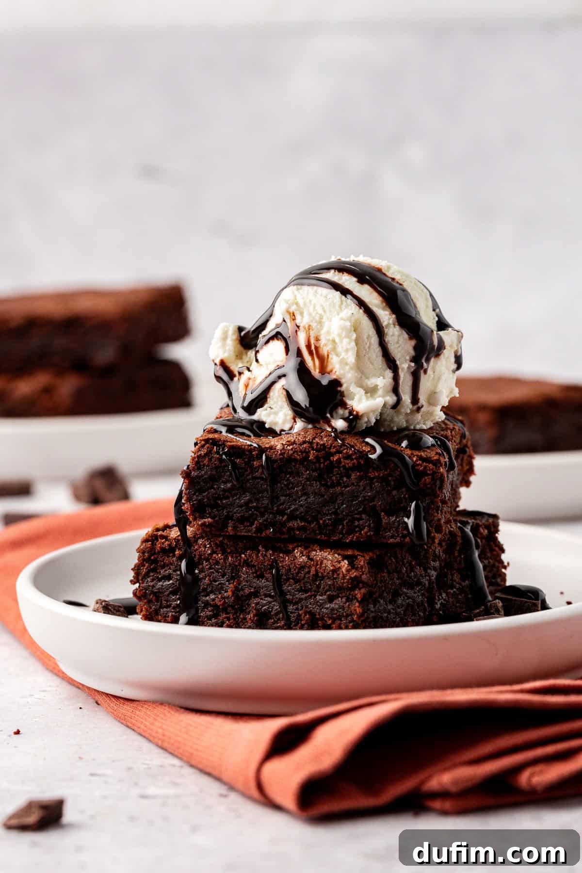 Decadent Chocolate Brownies 20 A delectable homemade brownie topped with a scoop of vanilla ice cream and drizzled with warm hot fudge sauce, ready to be enjoyed as a decadent dessert.