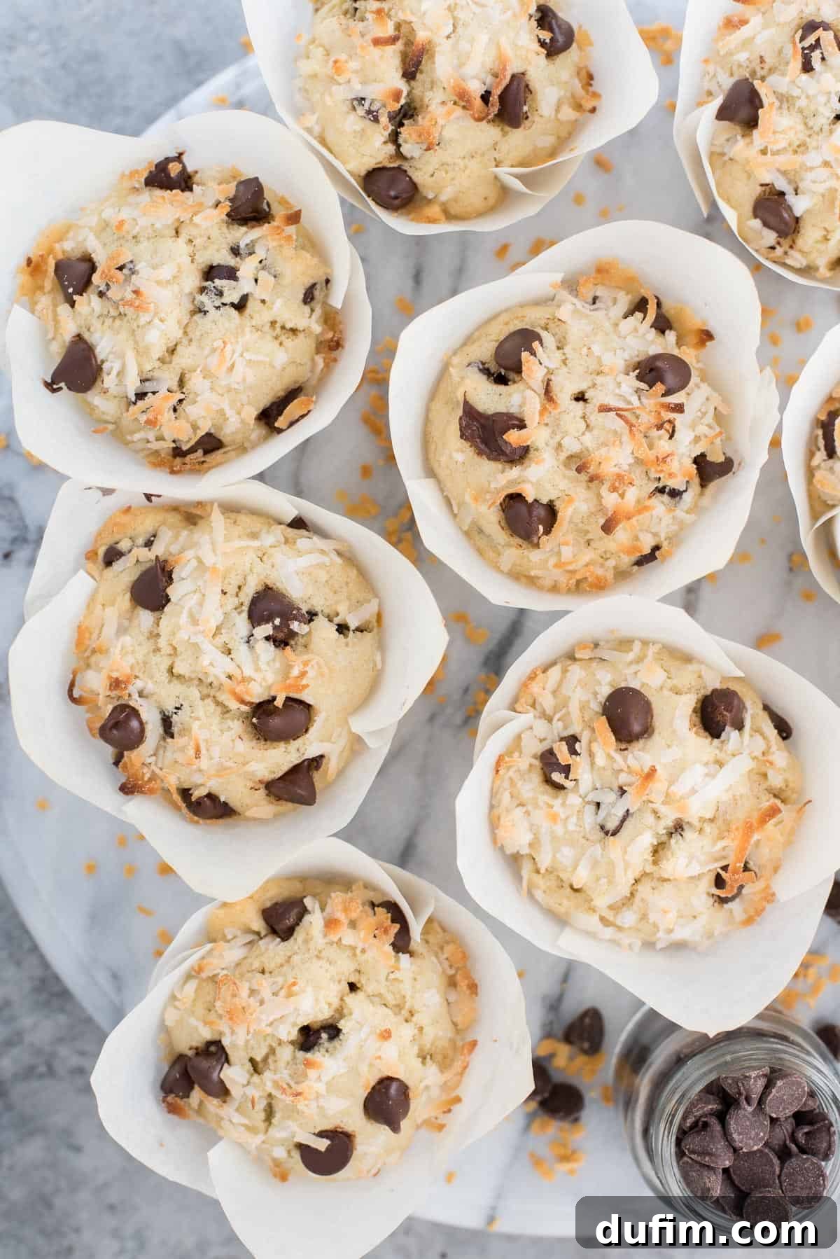 Tropical Coconut Chocolate Chip Muffins 6 An inviting aerial view of coconut chocolate chip muffins beautifully arranged on a round marble platter, ready for enjoyment.