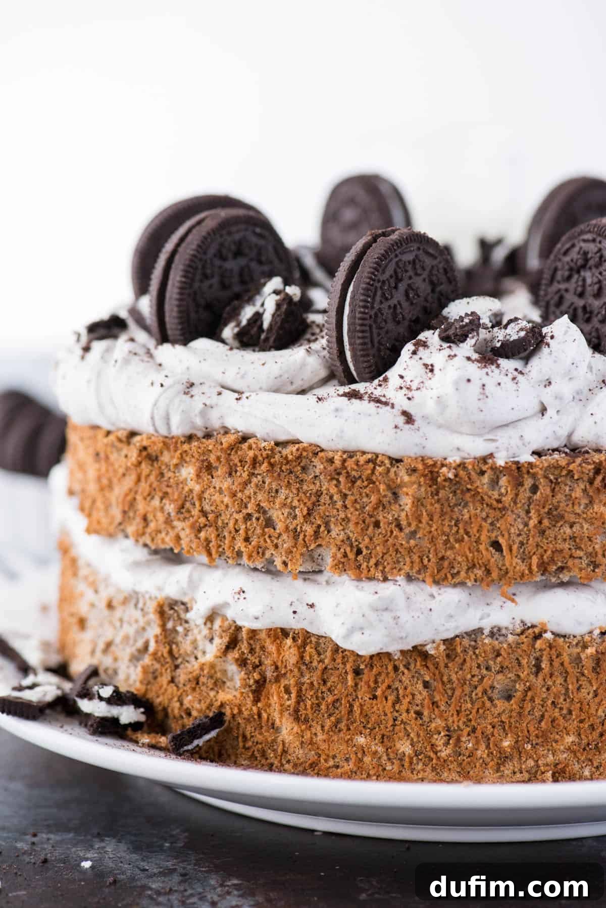 Oreo Angel Food Cake with Oreo whipped cream and crushed Oreo pieces on a white plate on a dark background