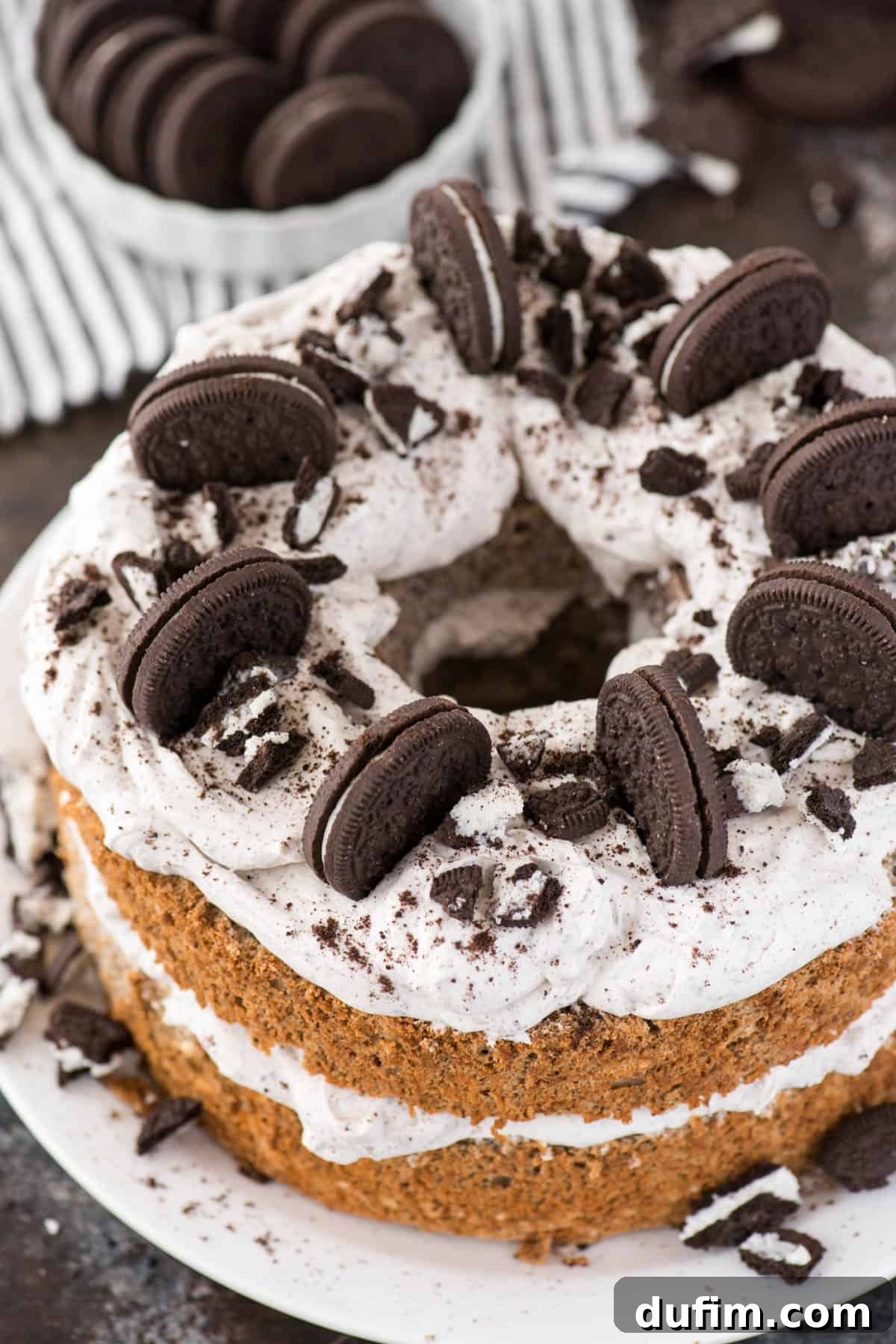 Oreo Angel Food Cake with Oreo whipped cream and crushed Oreo pieces on a white plate on a dark background