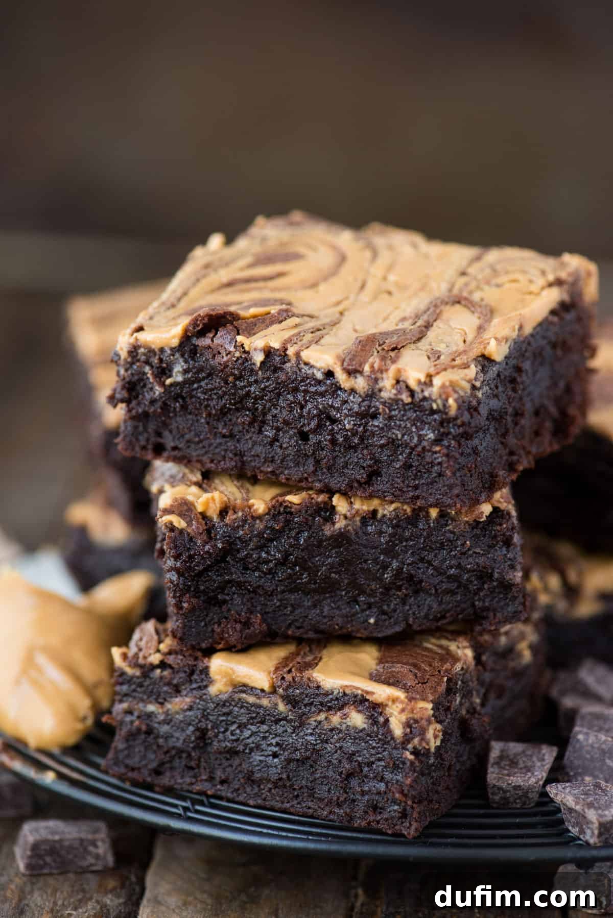 3 peanut butter swirl brownies stacked on each other on dark background