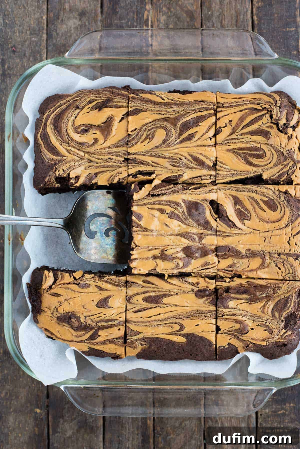 peanut butter swirl brownies cut into squares in glass pan on dark background