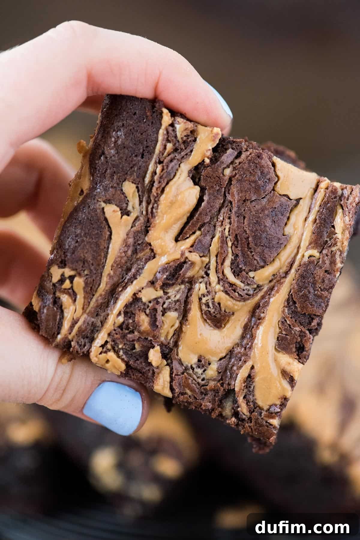 close up of fingers holding a peanut butter swirl brownie