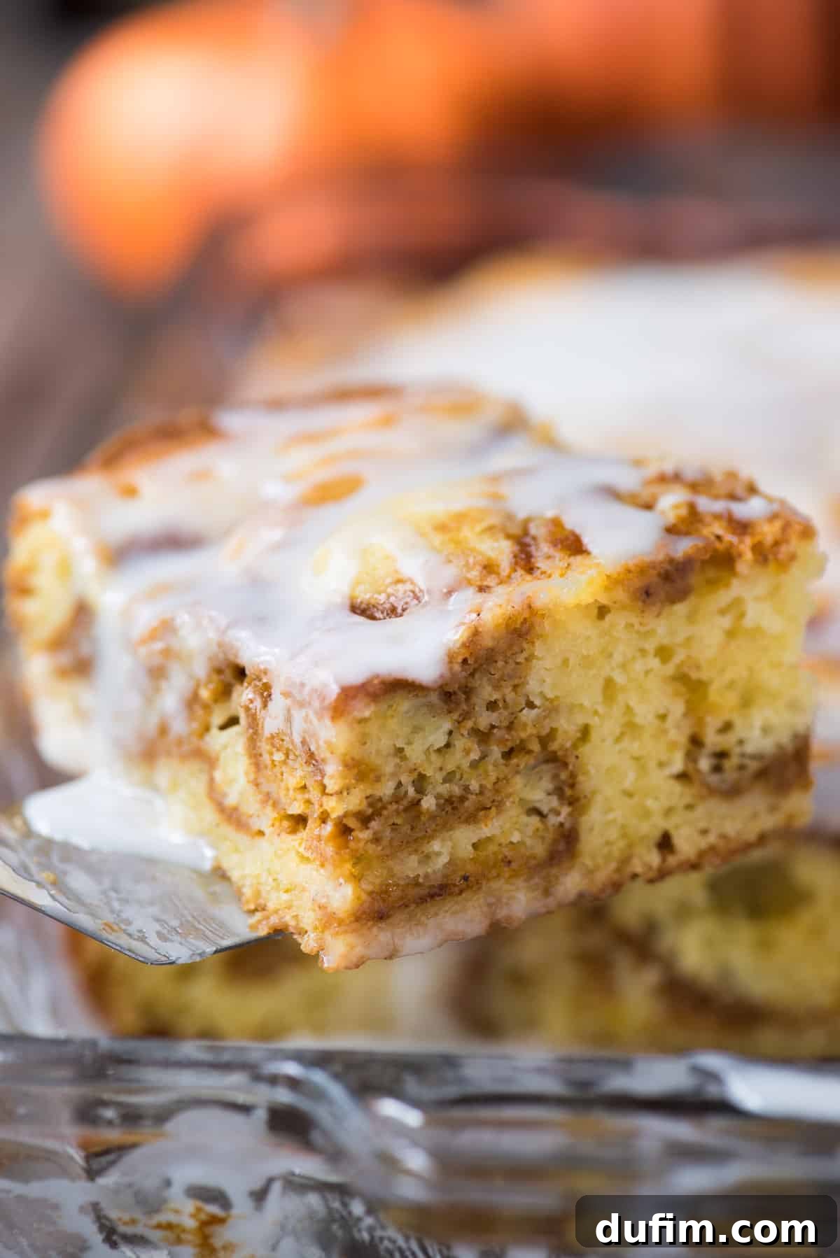A perfectly portioned slice of golden yellow cake featuring beautiful pumpkin swirls, served on a sleek metal spatula. The cake is moist and inviting, ready to be enjoyed.