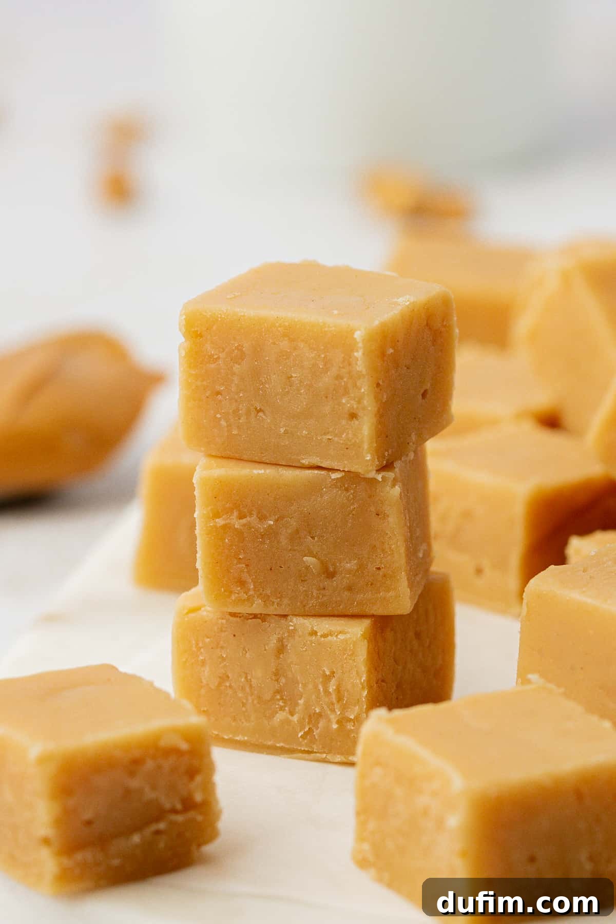 Three pieces of golden-brown peanut butter fudge stacked on top of each other, showcasing their smooth texture