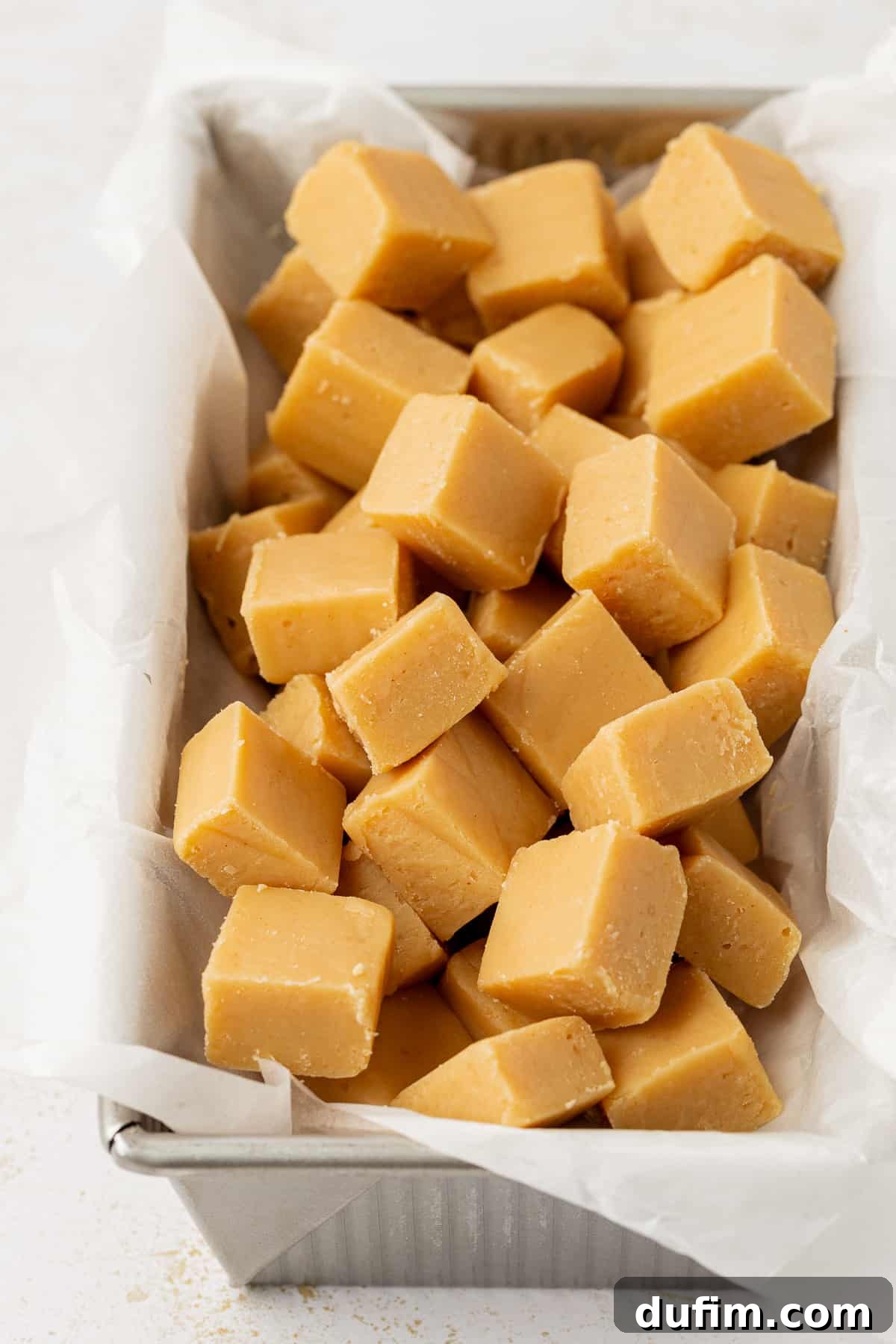 Peanut butter fudge cut into small squares and beautifully displayed in a loaf pan