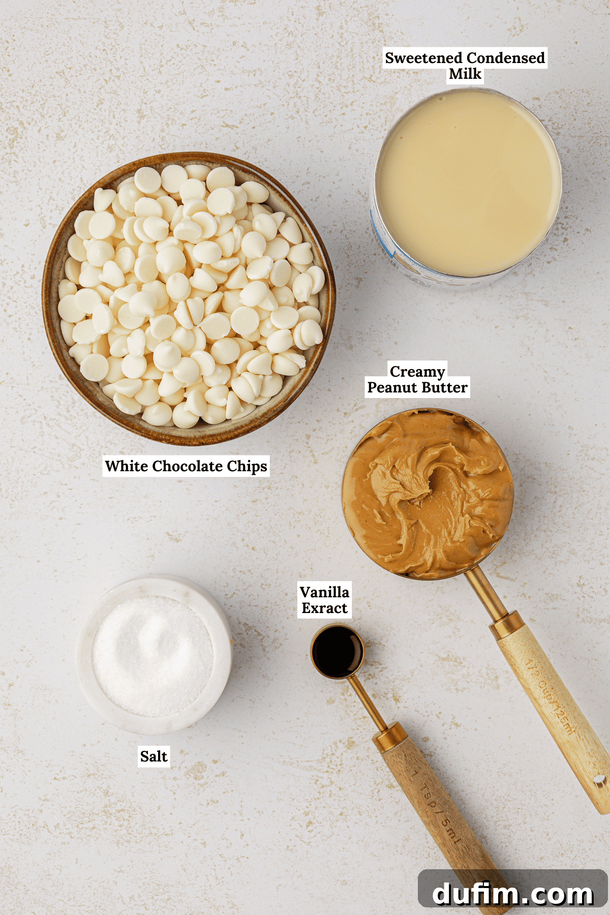 An overhead view showcasing all the simple ingredients required to make delicious peanut butter fudge: white chocolate chips, peanut butter, sweetened condensed milk, salt, and vanilla extract