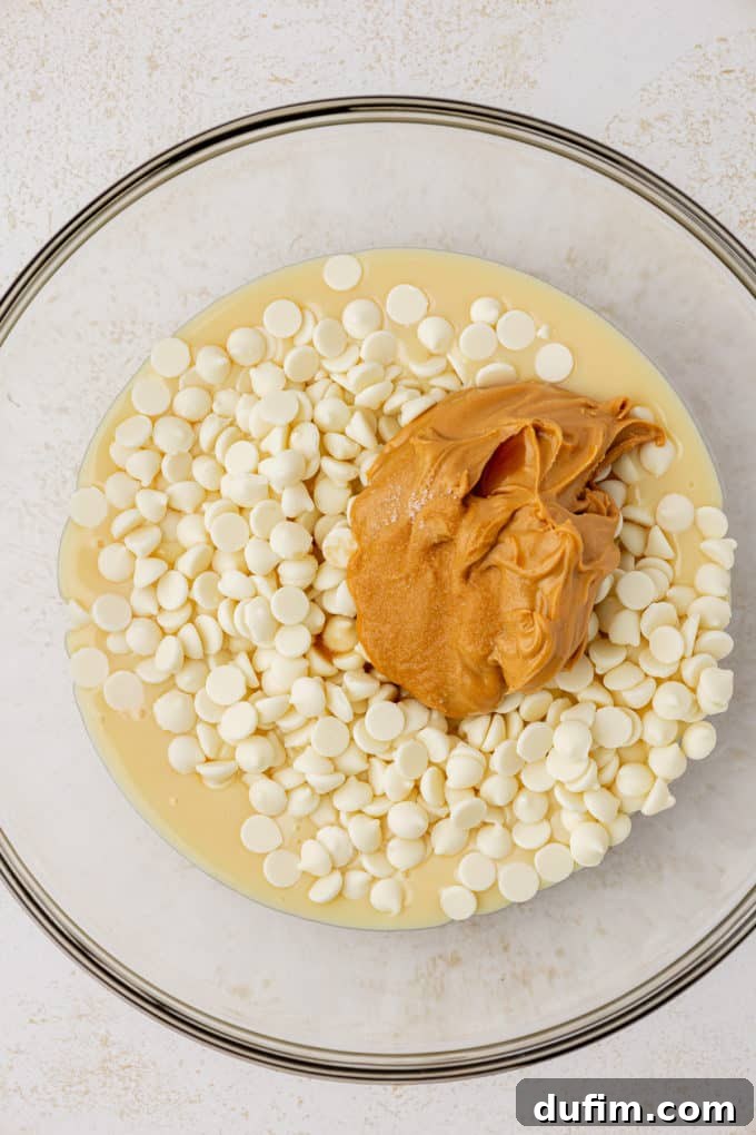 White chocolate chips, creamy peanut butter, and sweetened condensed milk waiting to be microwaved in a clear glass bowl