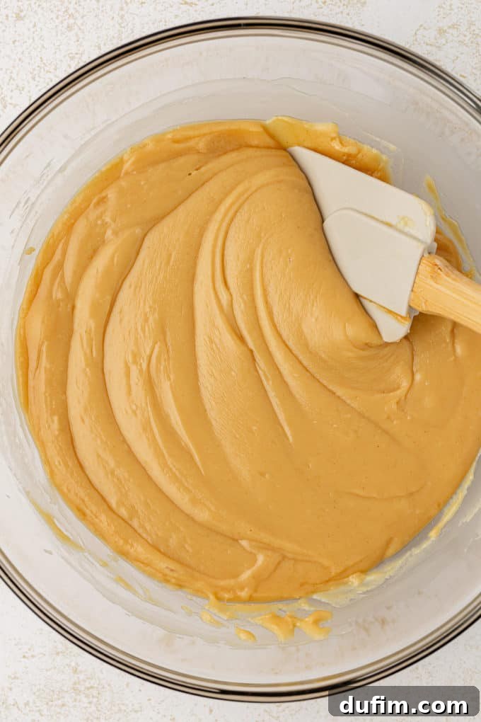 The smooth, melted mixture of white chocolate chips, peanut butter, and sweetened condensed milk in a glass bowl after microwaving