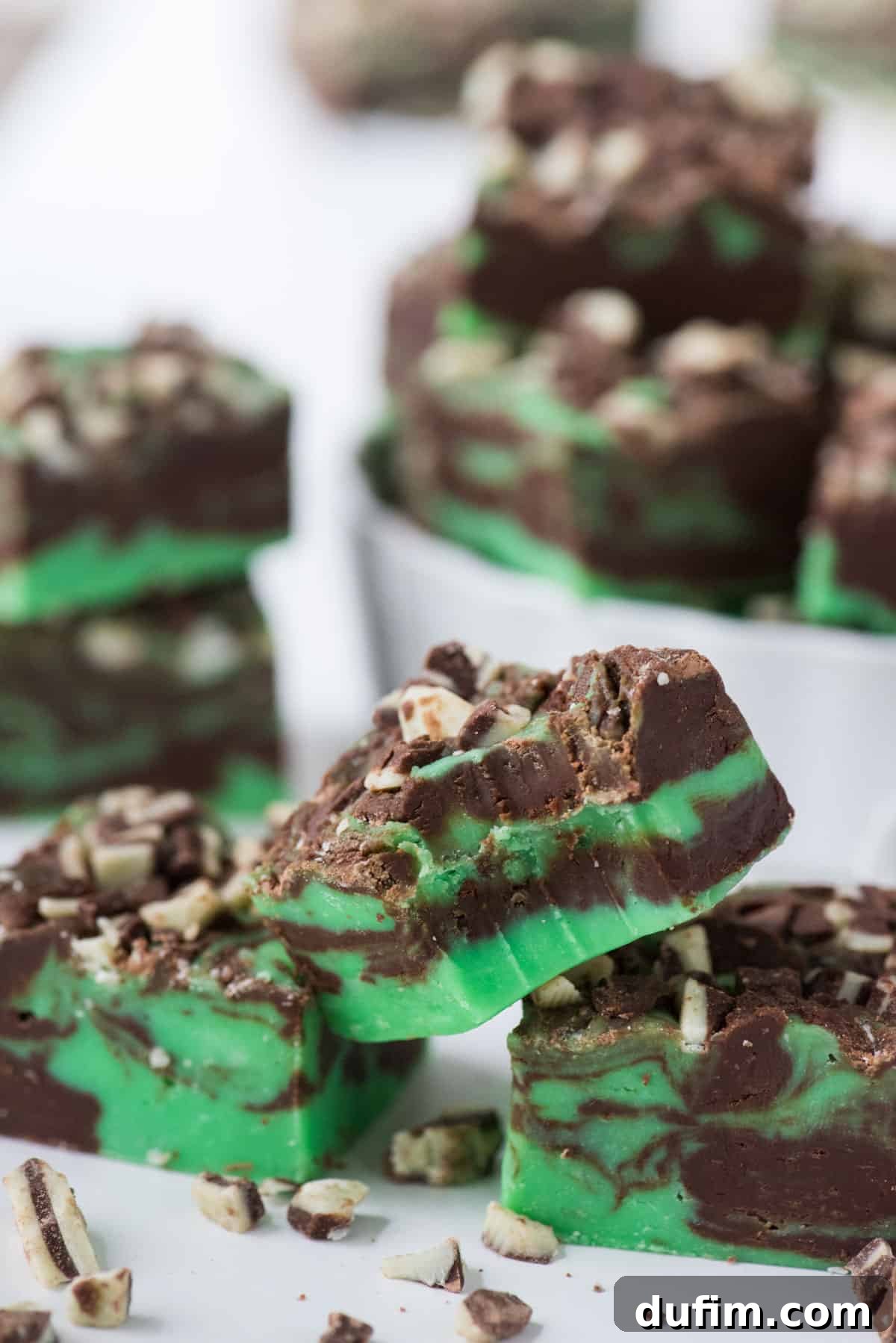 Delicate pieces of mint chocolate fudge artfully arranged on a clean white background, highlighting their exquisite texture and color.