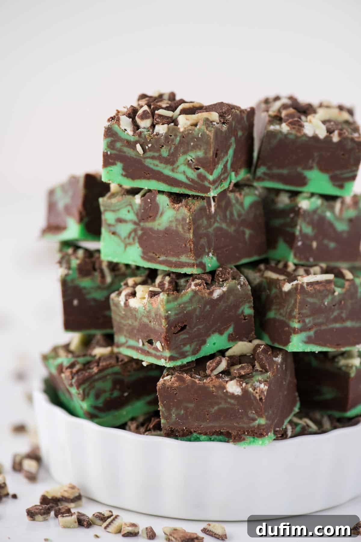 Neatly stacked pieces of mint chocolate fudge in a small white bowl, ready for a delicious treat.