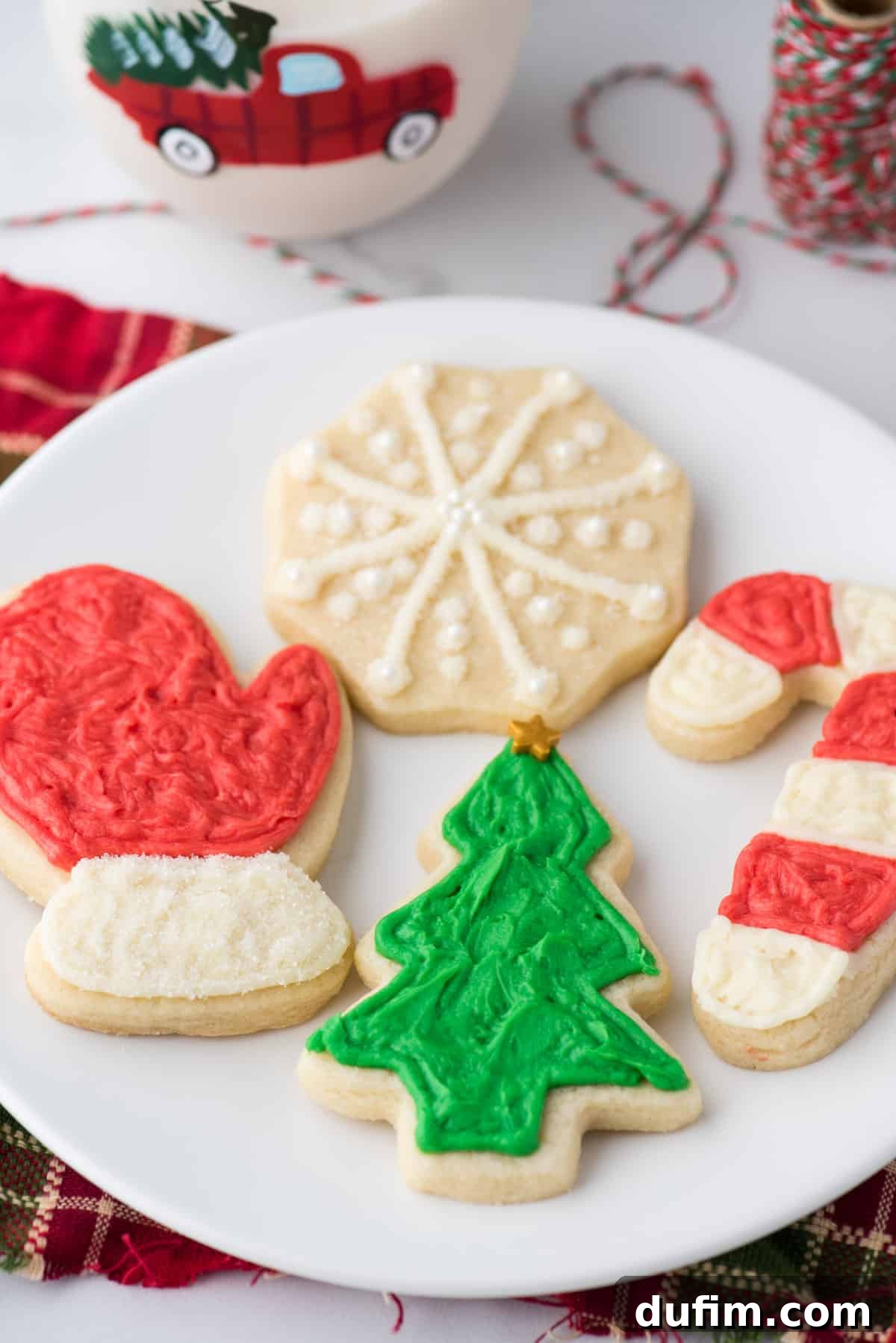 Beautifully decorated cut out Christmas sugar cookies arranged artfully on a white plate, showcasing their perfect shapes and vibrant frosting designs.