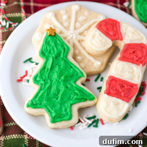 Delicious cut-out sugar cookies ready for decorating, with various cookie cutters in the background.