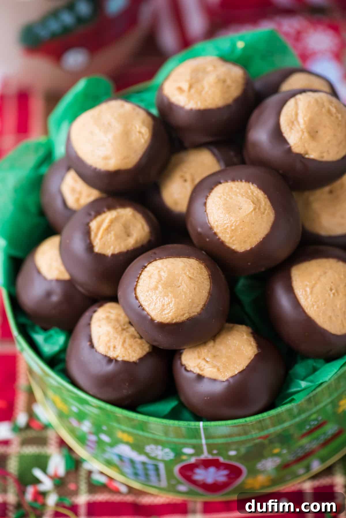 Sweet & Salty Homemade Peanut Butter Buckeye Bites 2 Peanut butter balls in a green Christmas cookie tin, resting on a red striped towel background.