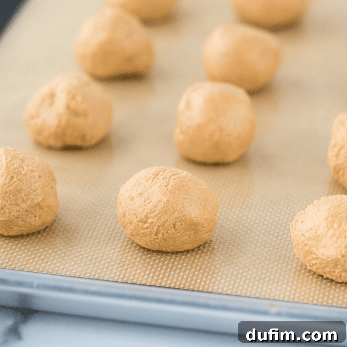 Sweet & Salty Homemade Peanut Butter Buckeye Bites 6 Perfectly formed peanut butter balls arranged in a neat grid pattern on a silicone mat, ready for chilling.