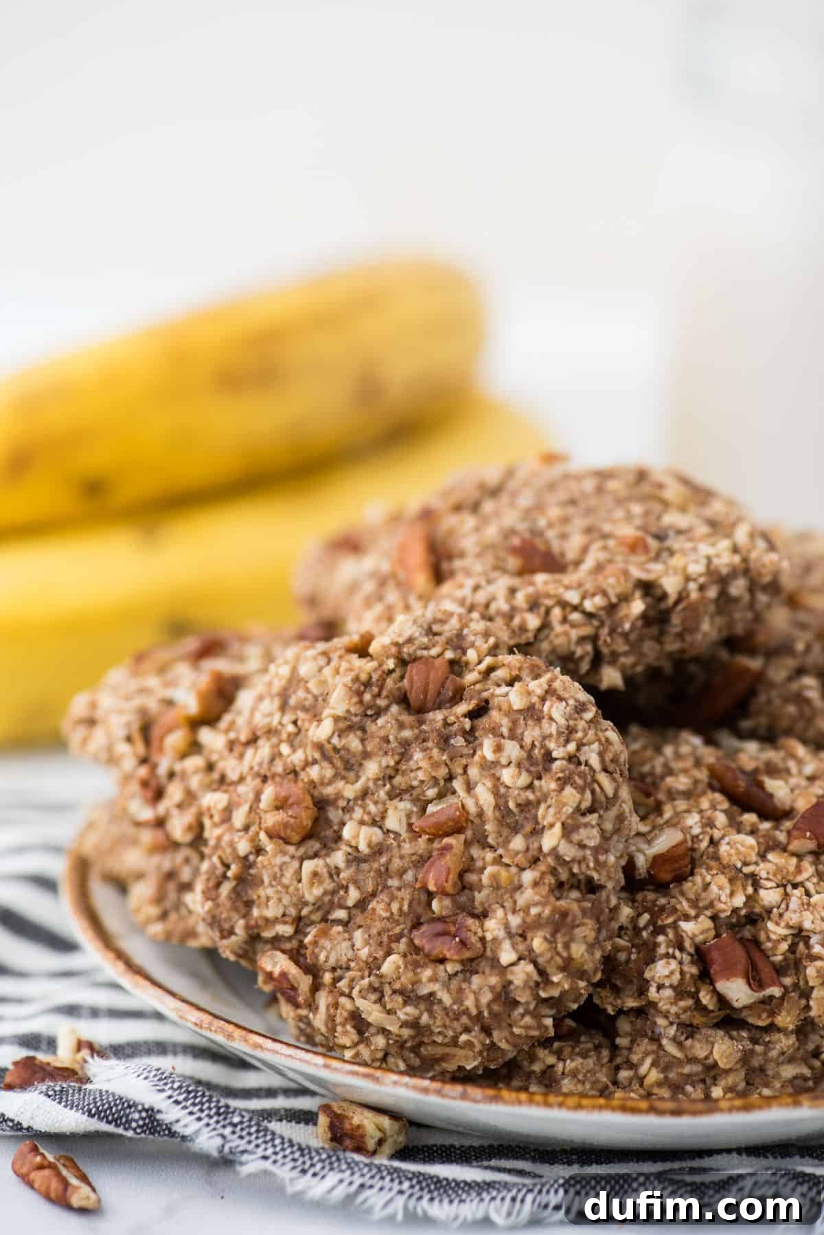 Healthy banana breakfast cookies arranged on a white plate with a striped towel underneath