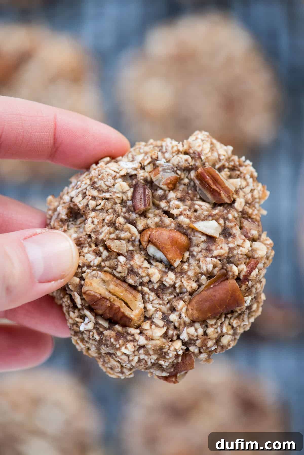 Close-up shot of a hand holding a healthy banana breakfast cookie, showing its texture