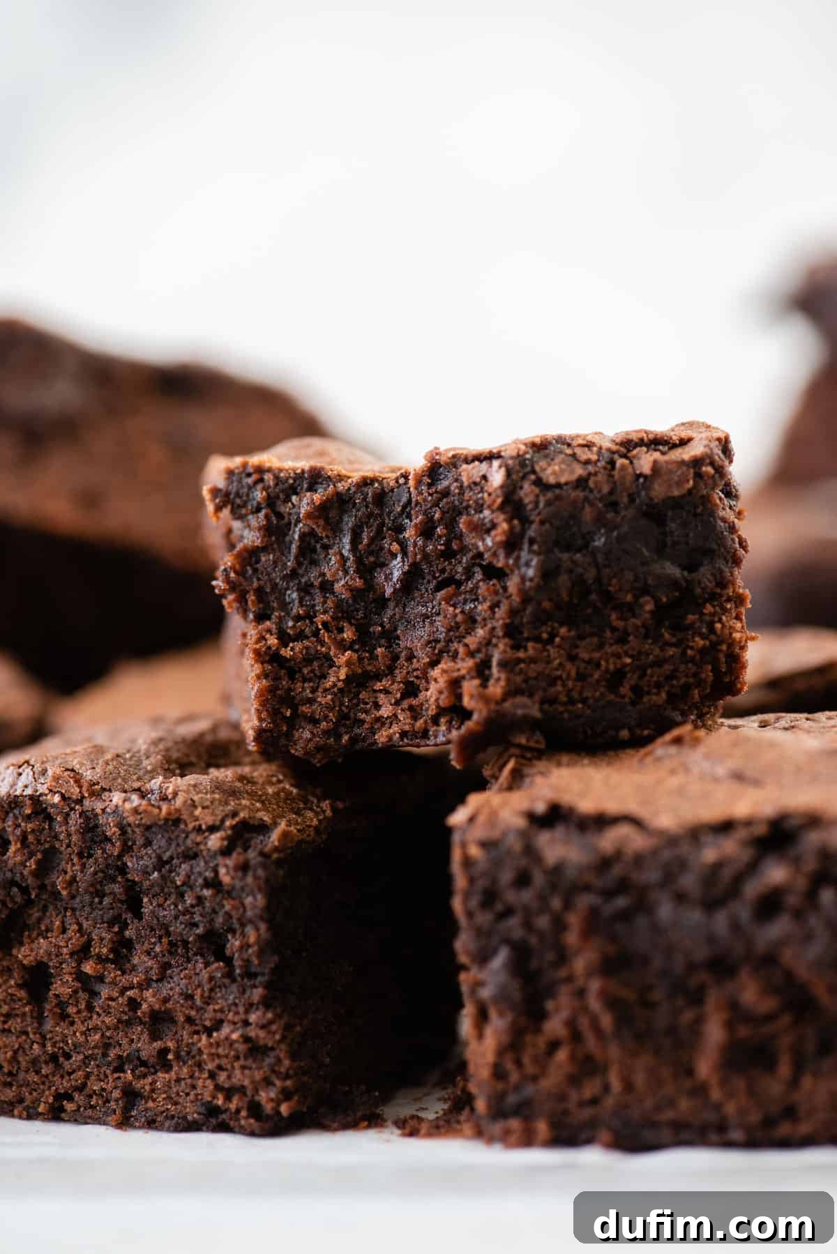 A stack of perfectly cut fudgy brownie squares, showcasing their rich texture and moist interiors, ready to be enjoyed.