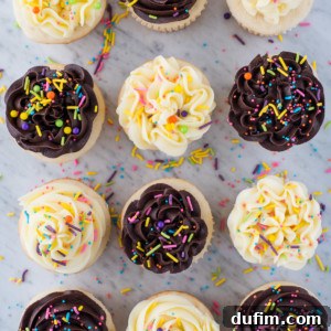 Twelve easy white cupcakes with swirled chocolate and vanilla frosting, topped with colorful sprinkles, are arranged neatly on a white marble surface. A few scattered sprinkles surround the cupcakes.