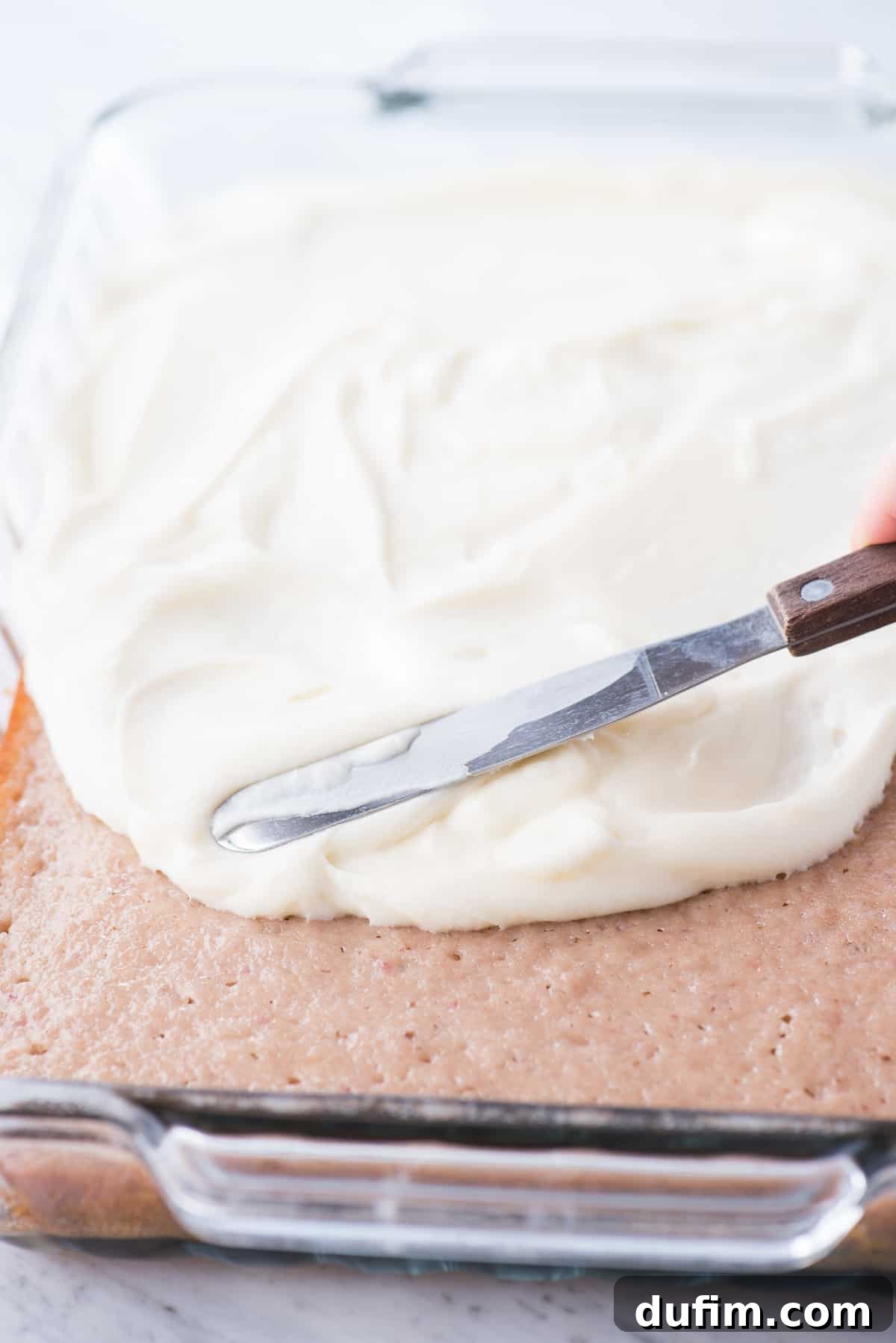 Homemade Cream Cheese Frosting Perfection 3 Cream cheese frosting being spread onto a cake, showing its smooth consistency.
