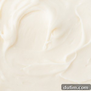 Close-up of smooth, creamy homemade cream cheese frosting spread evenly with visible swirls and soft peaks.