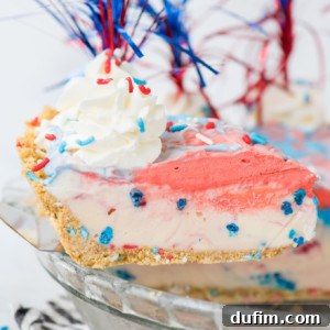 A slice of 4th of July Pie with patriotic red, white, and blue ice cream, a graham cracker crust, whipped cream, festive sprinkles, and decorative red, white, and blue tinsel picks.