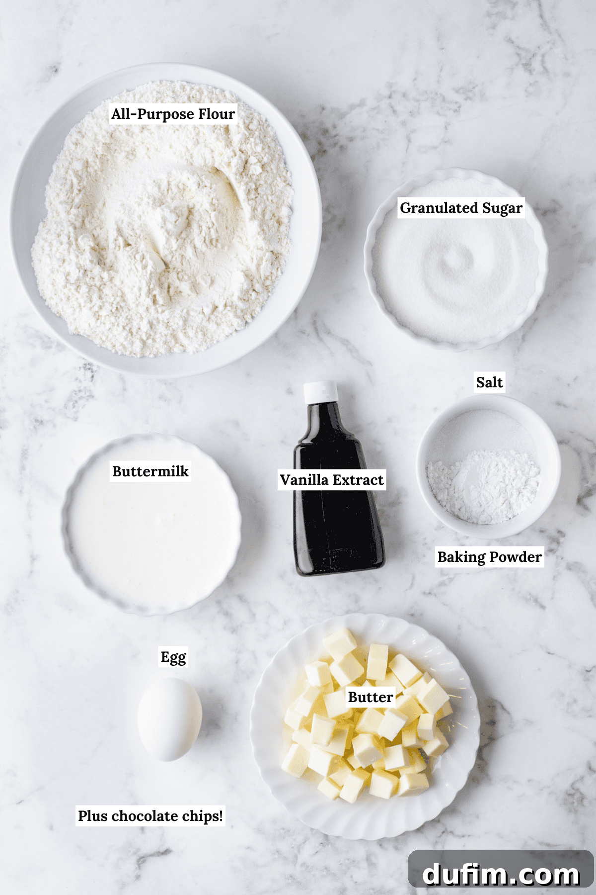 Gourmet Chocolate Chip Buttermilk Scones 5 A flat lay photograph displaying all the essential ingredients for chocolate chip scones: flour, sugar, butter, buttermilk, egg, vanilla, baking powder, salt, and chocolate chips.