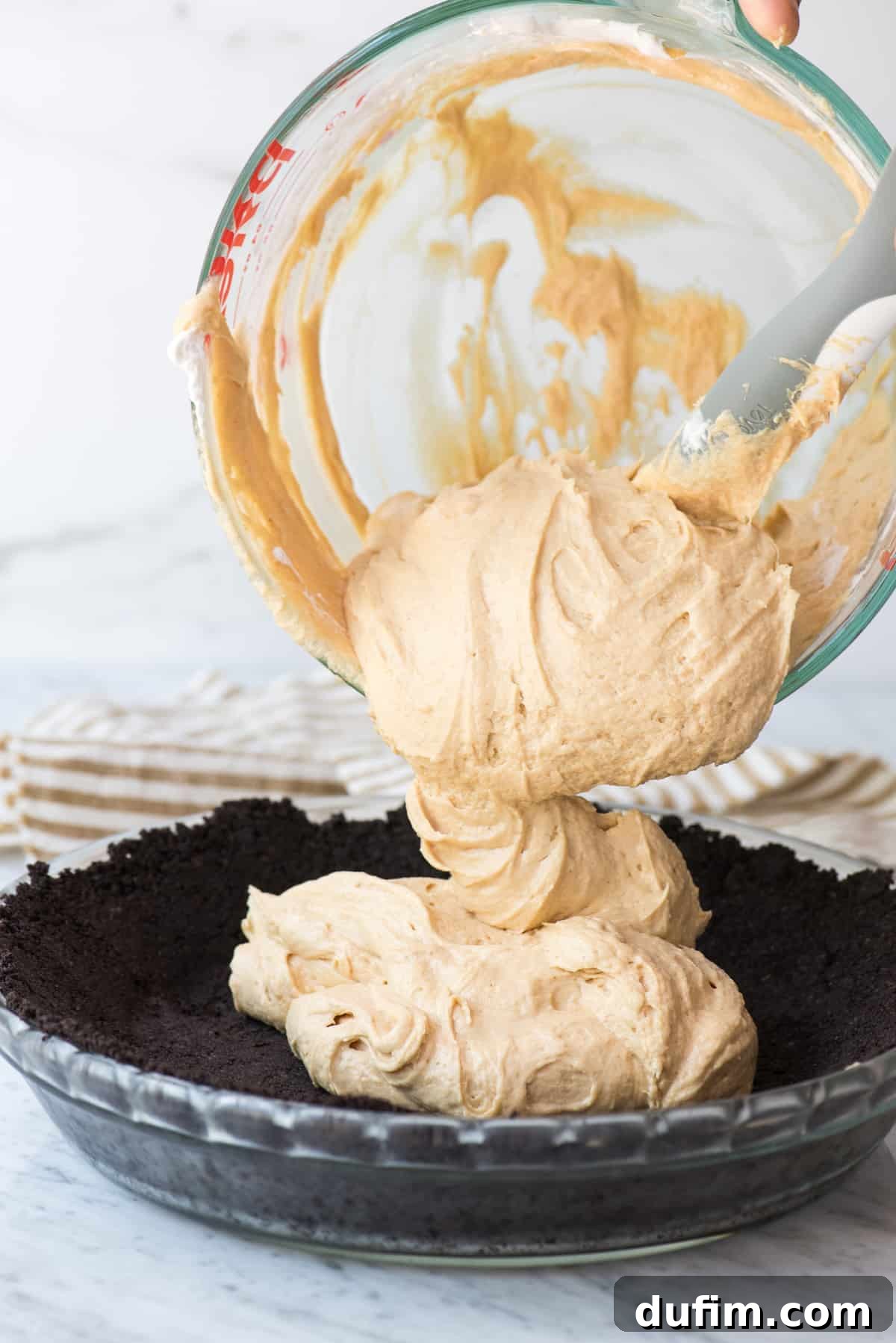 peanut butter filling being put into oreo pie crust