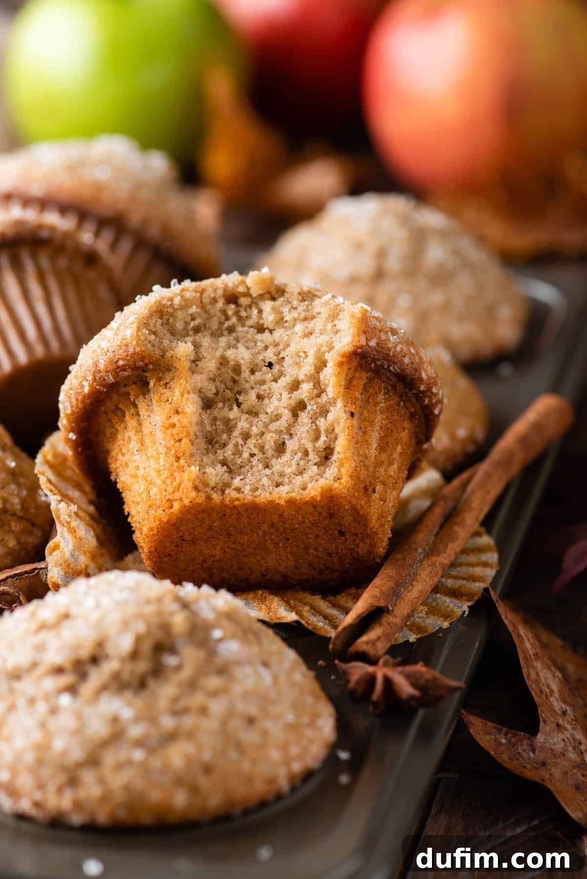 Freshly baked applesauce muffins cooling in a metal muffin pan, showcasing their golden-brown tops.