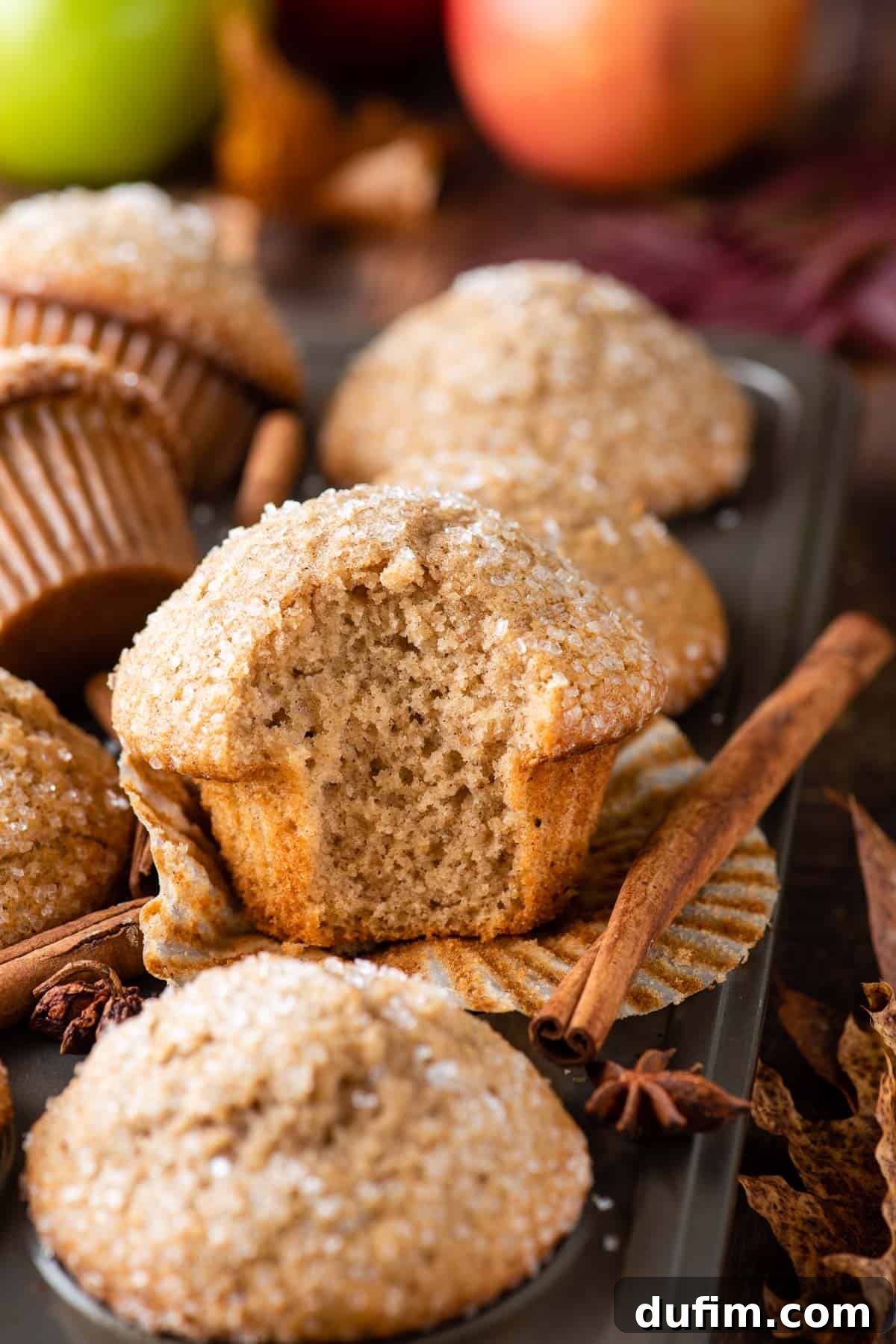 Perfectly baked applesauce muffins cooling in a metal muffin pan, showing their appealing golden tops.