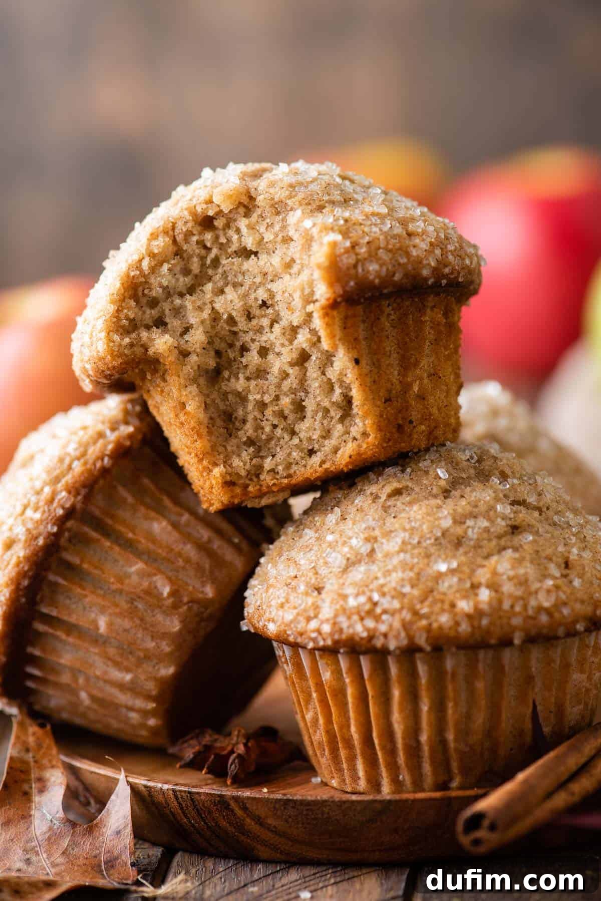 Three golden-brown applesauce muffins stacked neatly on a rustic wooden plate, ready to be enjoyed.