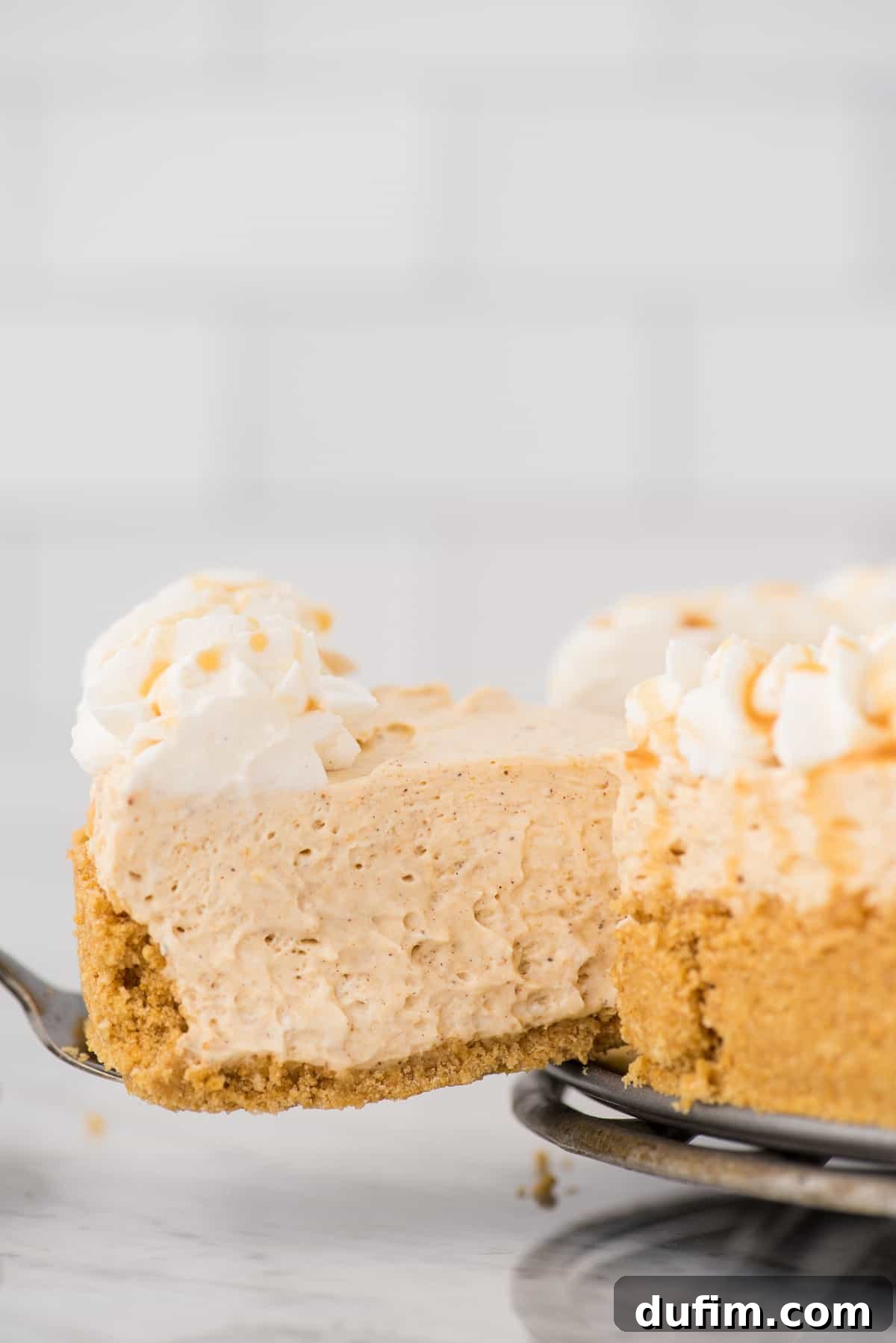 Effortless Spiced Pumpkin Cheesecake 5 slice of pumpkin cheesecake being removed from the cheesecake on a metal spatula