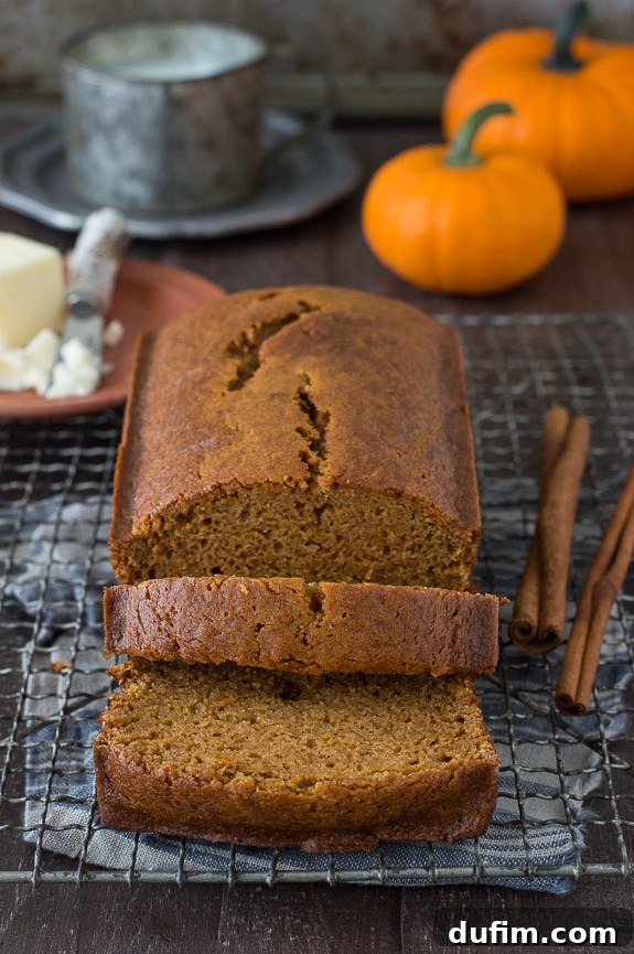 Starbucks Inspired Pumpkin Bread Perfection 6 Two slices of a golden-brown, moist pumpkin bread loaf displayed on a cooling rack, highlighting its tender crumb and rich texture, perfect for a cozy fall treat.