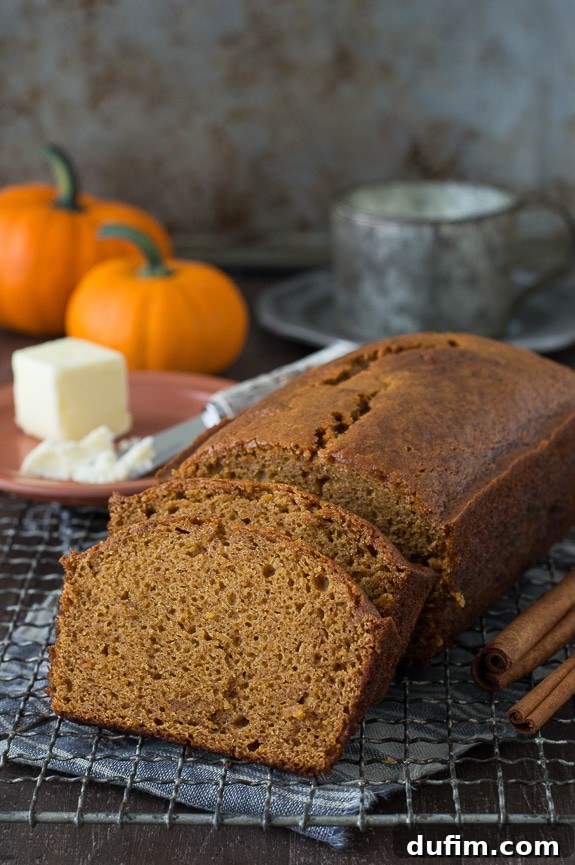 Starbucks Inspired Pumpkin Bread Perfection 7 Close-up of a perfectly sliced pumpkin bread loaf on a metal cooling rack, showing its inviting texture and golden-brown crust. The slices are ready for serving or storing.